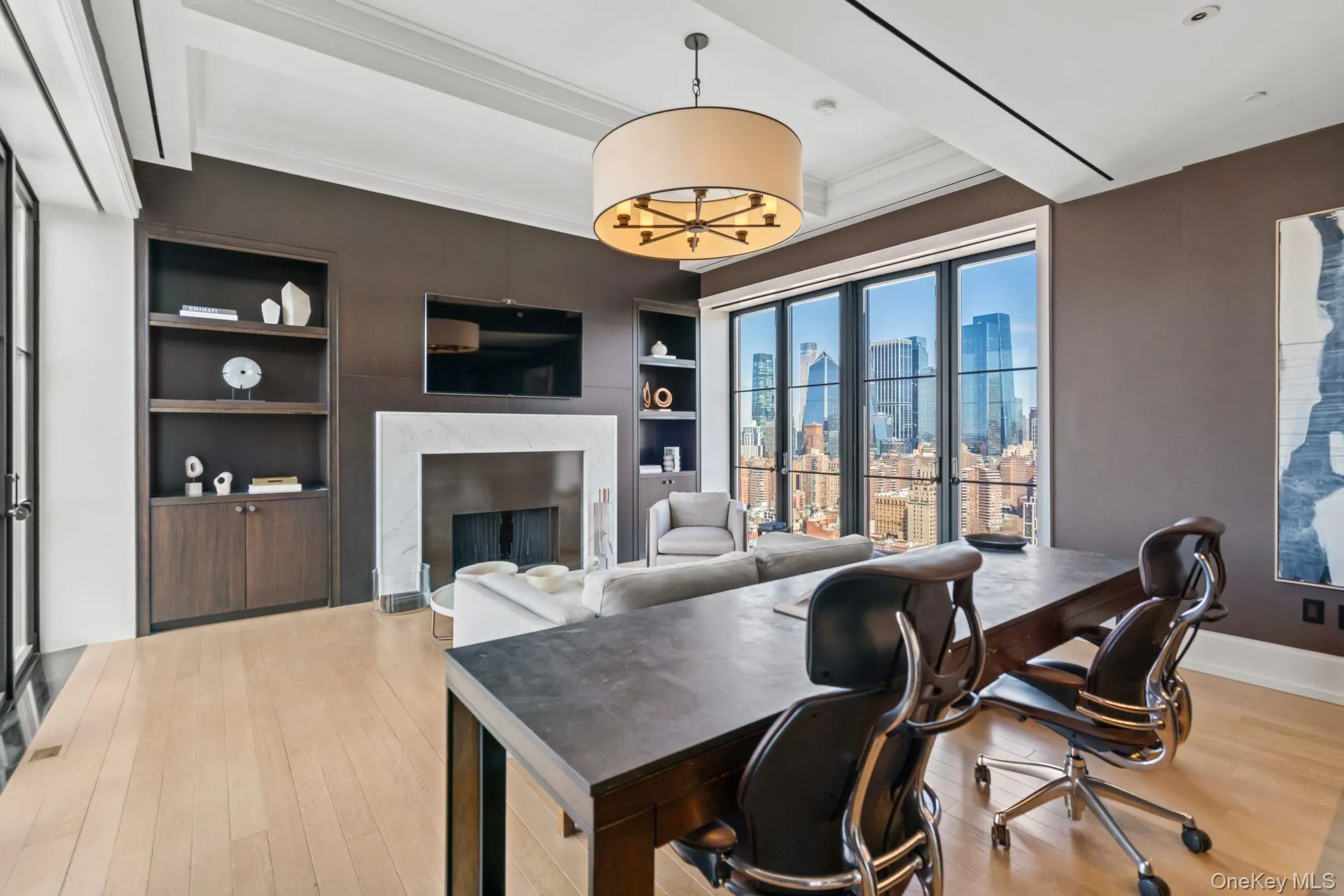 Office area featuring baseboards, built in shelves, beam ceiling, a high end fireplace, and wood finished floors Office area featuring baseboards, built in shelves, beam ceiling, a high end fireplace, and wood finished floors