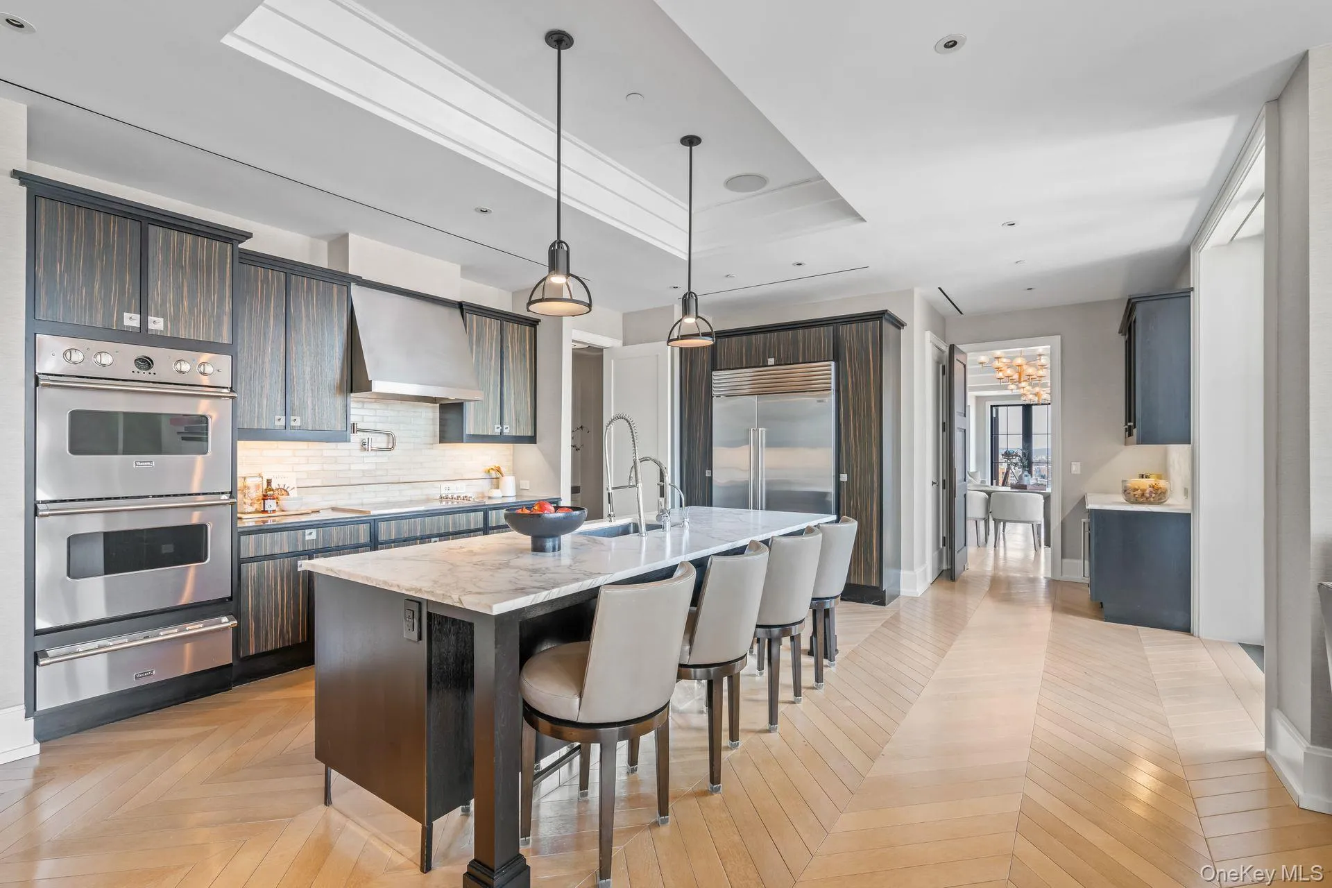 Kitchen with a warming drawer, a breakfast bar area, backsplash, wall chimney range hood, and appliances with stainless steel finishes Kitchen with a warming drawer, a breakfast bar area, backsplash, wall chimney range hood, and appliances with stainless steel finishes