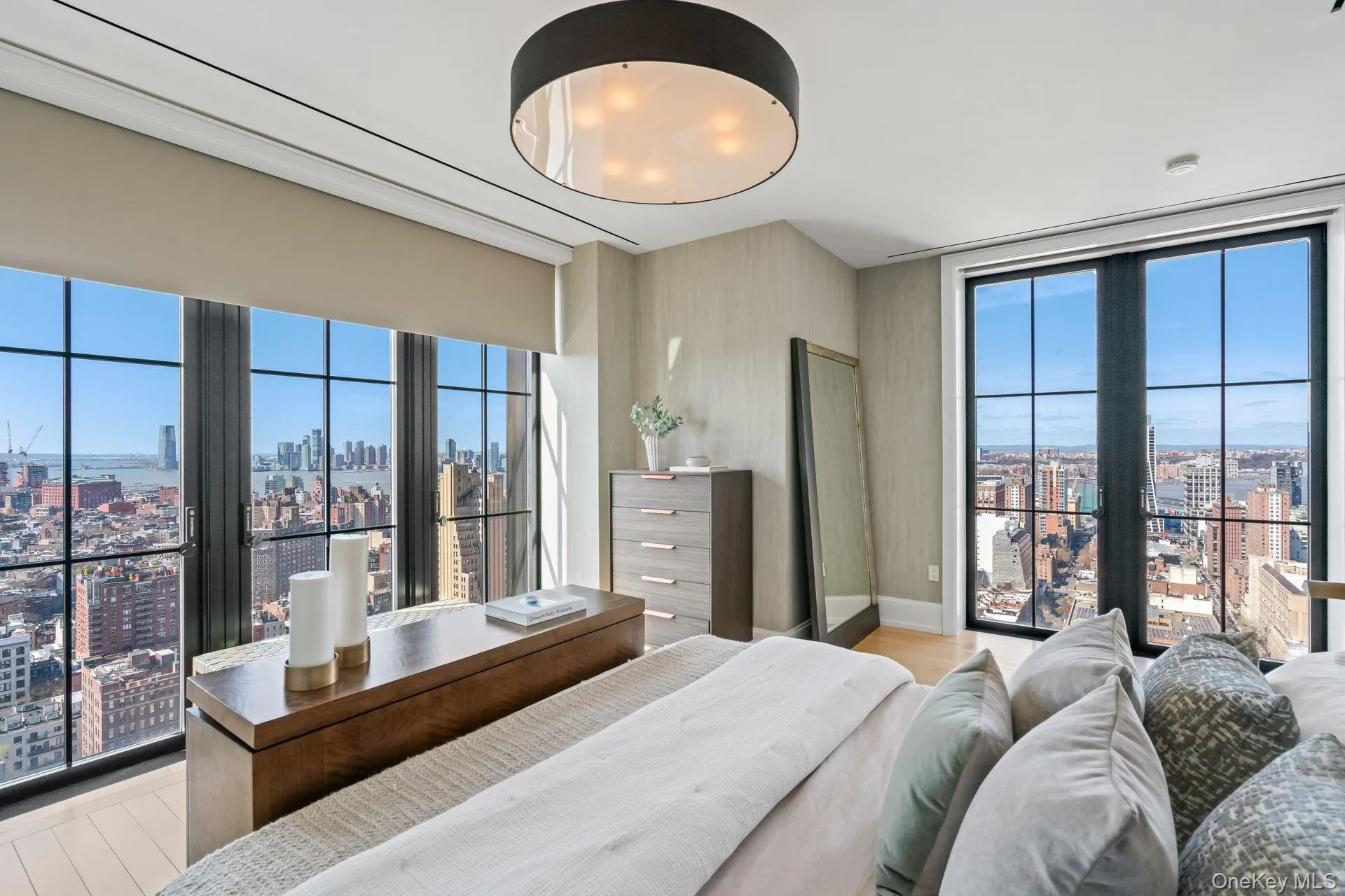 Bedroom featuring expansive windows, a view of city, and light wood-type flooring Bedroom featuring expansive windows, a view of city, and light wood-type flooring
