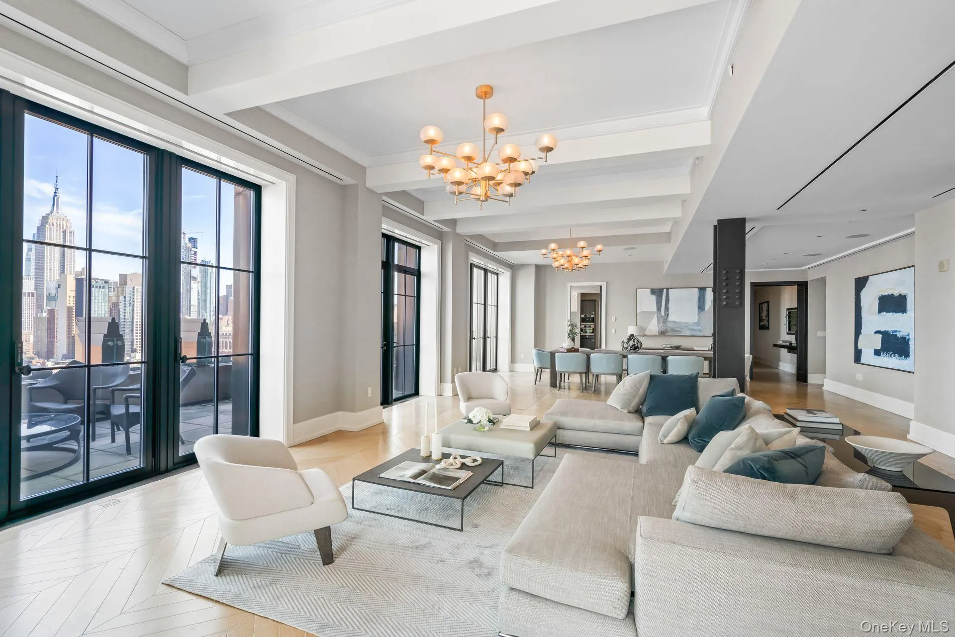 Living room with baseboards, crown molding, a notable chandelier, and beam ceiling Living room with baseboards, crown molding, a notable chandelier, and beam ceiling