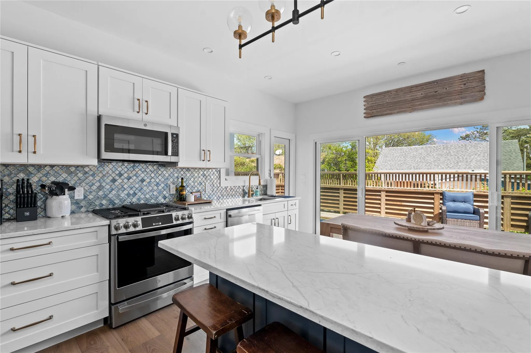 Kitchen featuring appliances with stainless steel finishes, a breakfast bar, tasteful backsplash, light stone countertops, and wood finished floors Kitchen featuring appliances with stainless steel finishes, a breakfast bar, tasteful backsplash, light stone countertops, and wood finished floors