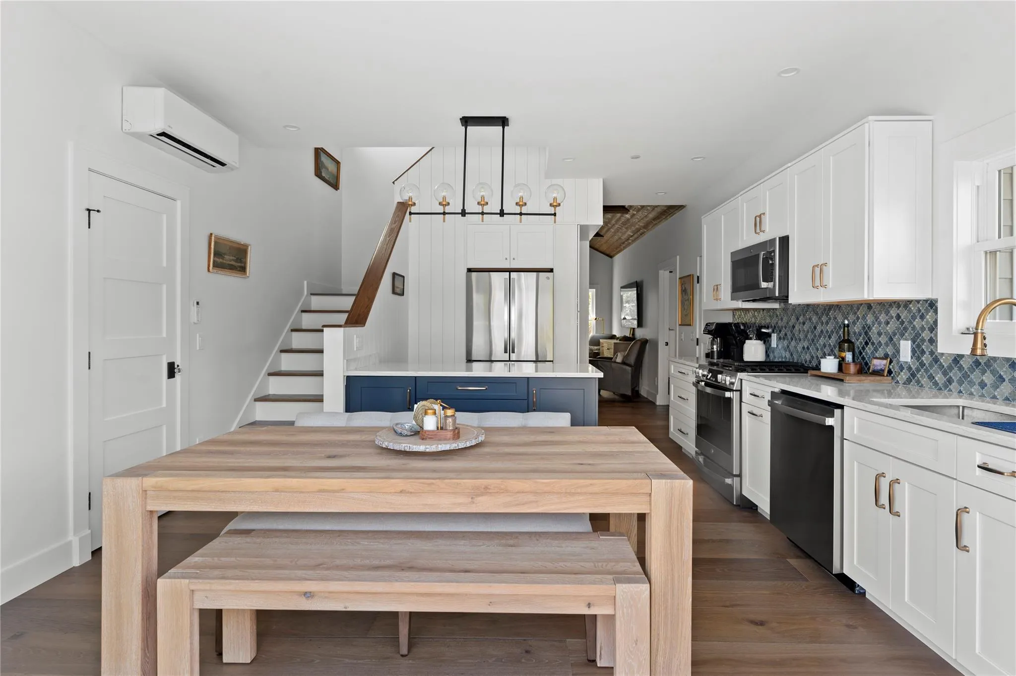 Kitchen featuring stainless steel appliances, a wall unit AC, a sink, and white cabinetry Kitchen featuring stainless steel appliances, a wall unit AC, a sink, and white cabinetry