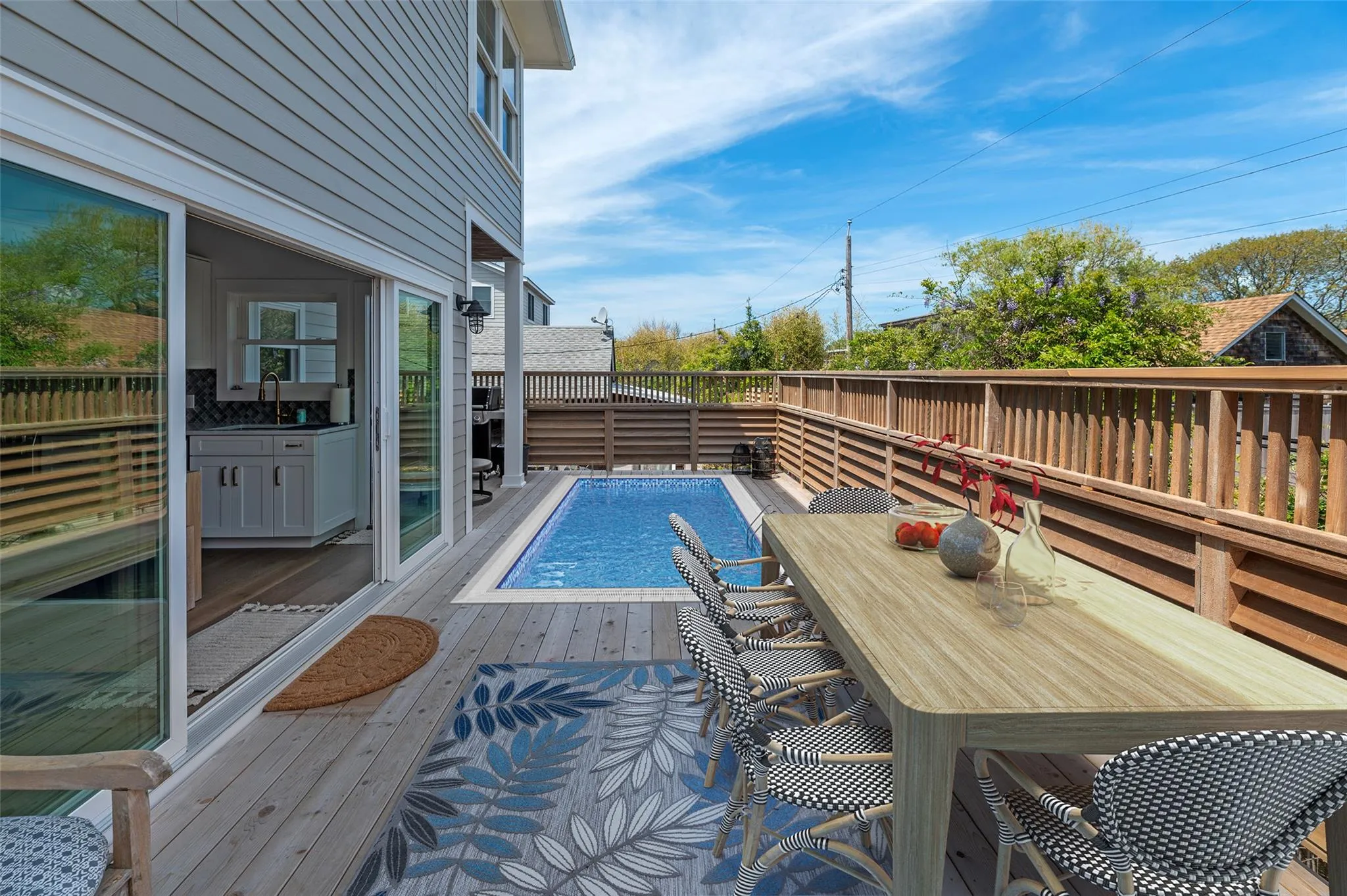 View of pool featuring a wooden deck, outdoor dining area, and a sink View of pool featuring a wooden deck, outdoor dining area, and a sink