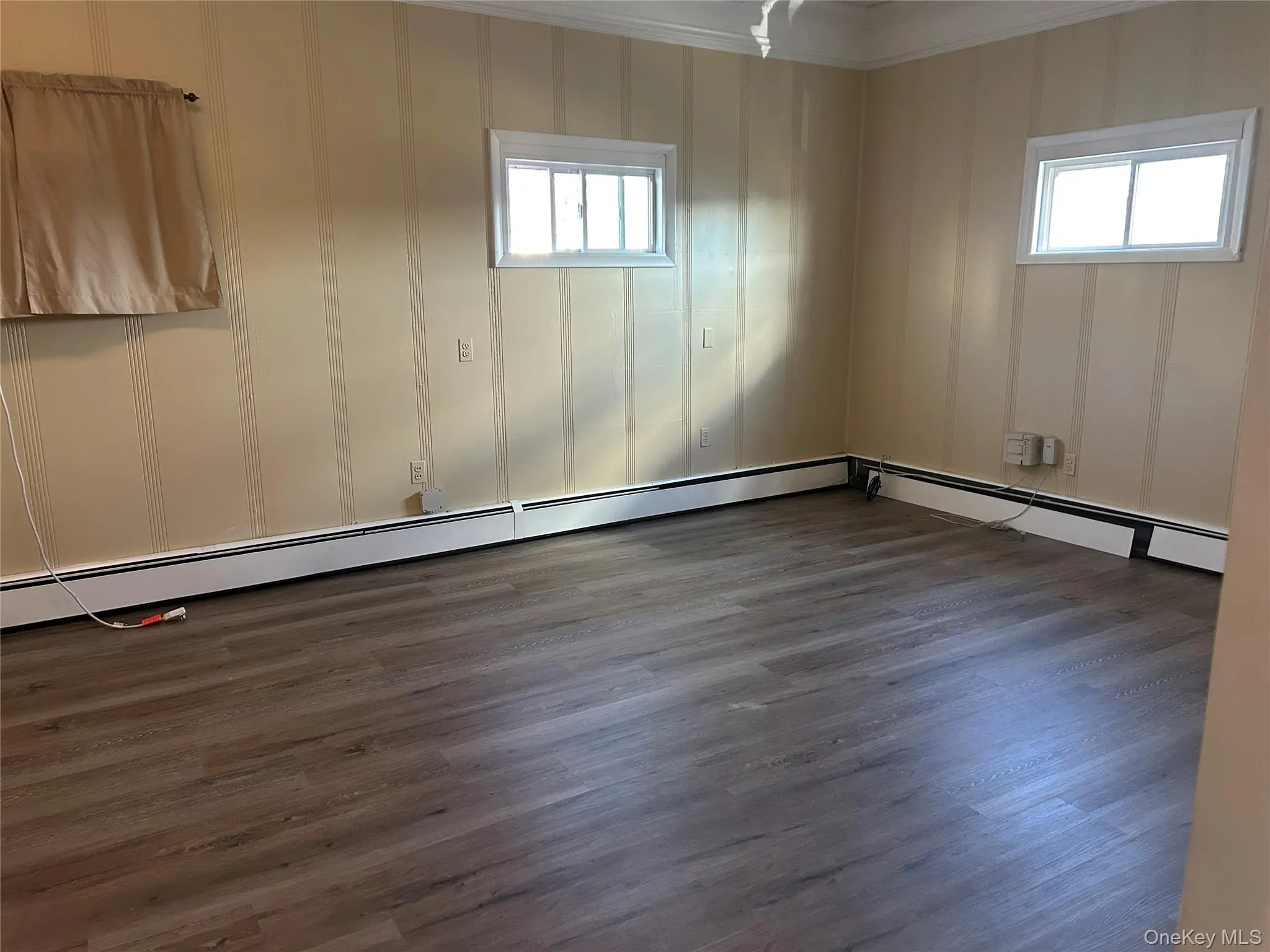 Unfurnished room with a healthy amount of sunlight, wood-type flooring, and ornamental molding Unfurnished room with a healthy amount of sunlight, wood-type flooring, and ornamental molding