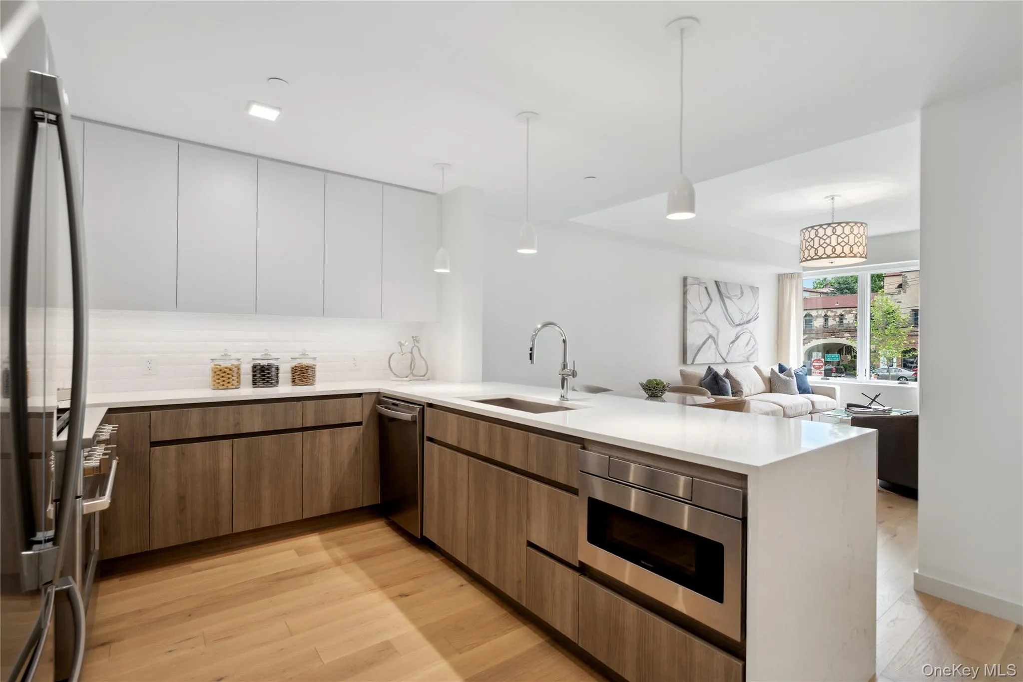 Kitchen with sink, light hardwood / wood-style flooring, decorative light fixtures, white cabinetry, and stainless steel appliances Kitchen with sink, light hardwood / wood-style flooring, decorative light fixtures, white cabinetry, and stainless steel appliances