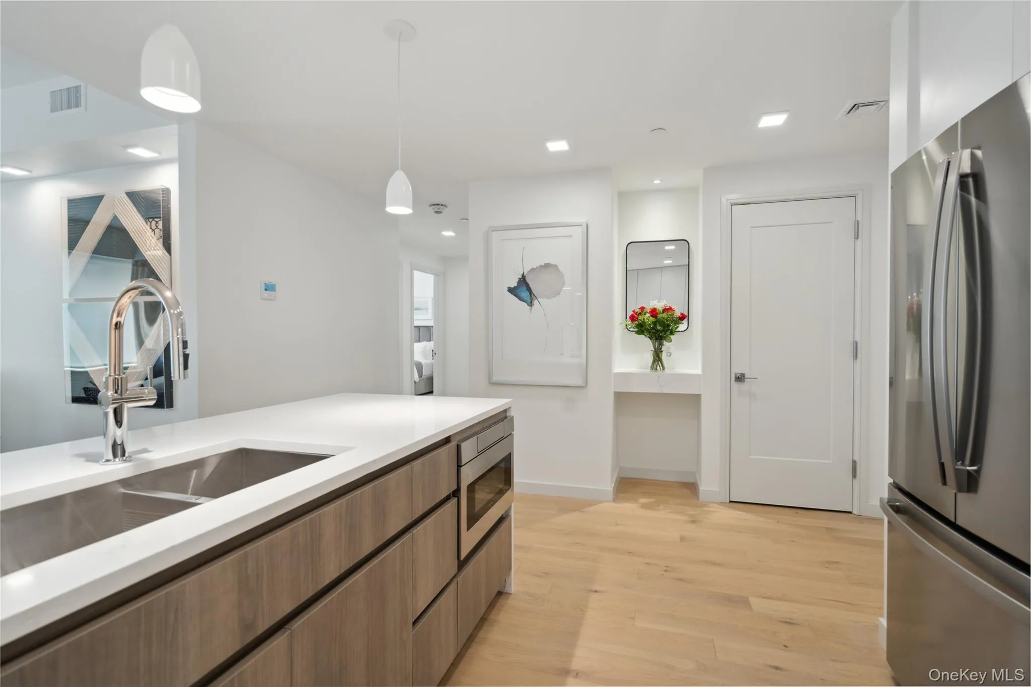 Kitchen featuring decorative light fixtures, stainless steel appliances, light hardwood / wood-style floors, and sink Kitchen featuring decorative light fixtures, stainless steel appliances, light hardwood / wood-style floors, and sink