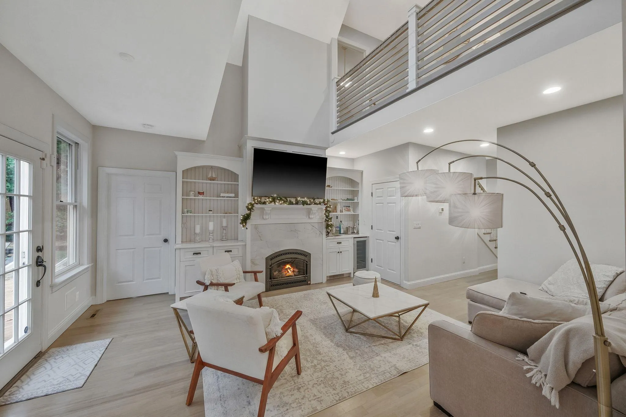 Living room featuring built in features, a towering ceiling, beverage cooler, and light hardwood / wood-style flooring Living room featuring built in features, a towering ceiling, beverage cooler, and light hardwood / wood-style flooring