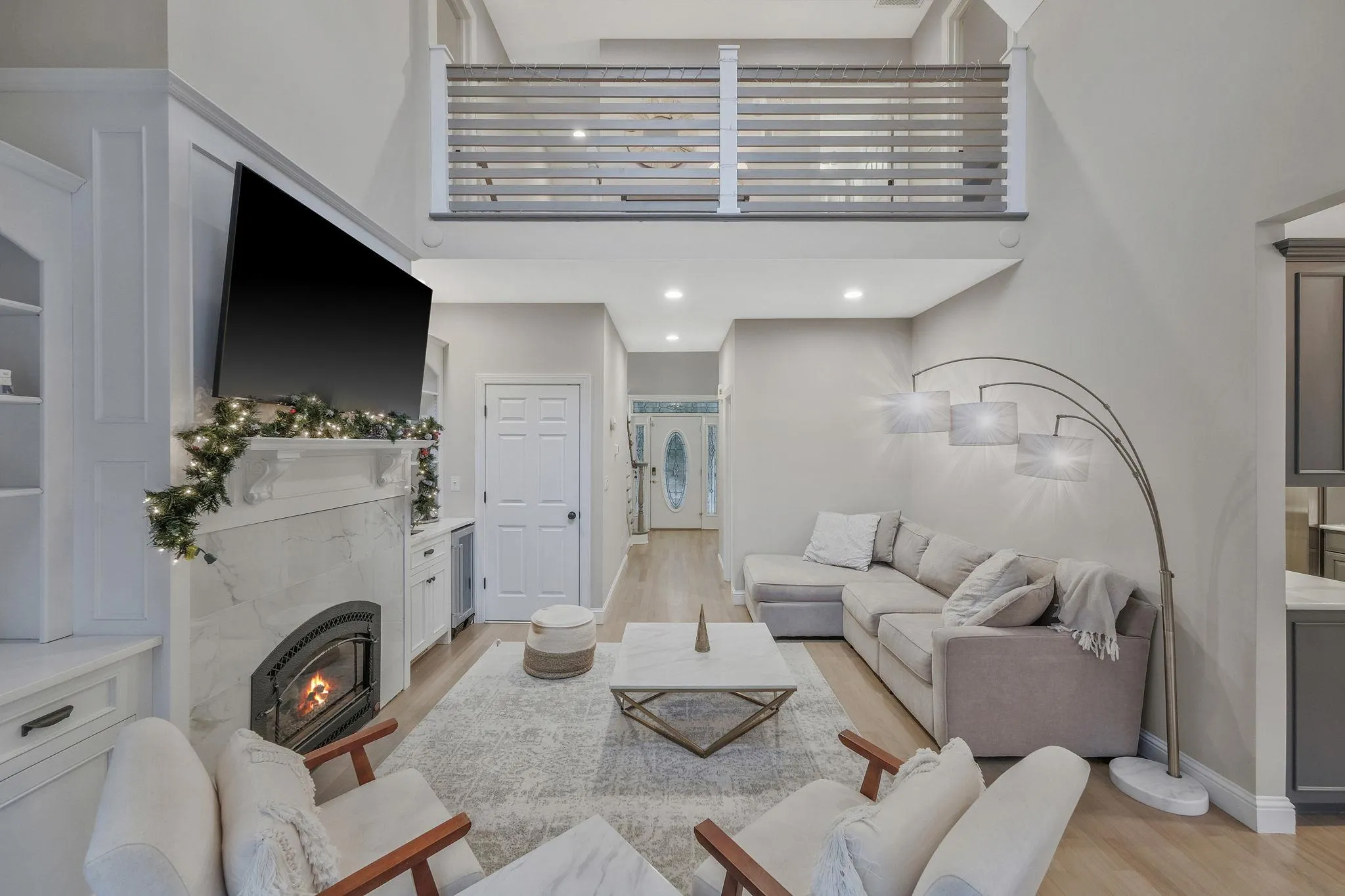 Living room with a tile fireplace, a high ceiling, and light wood-type flooring Living room with a tile fireplace, a high ceiling, and light wood-type flooring