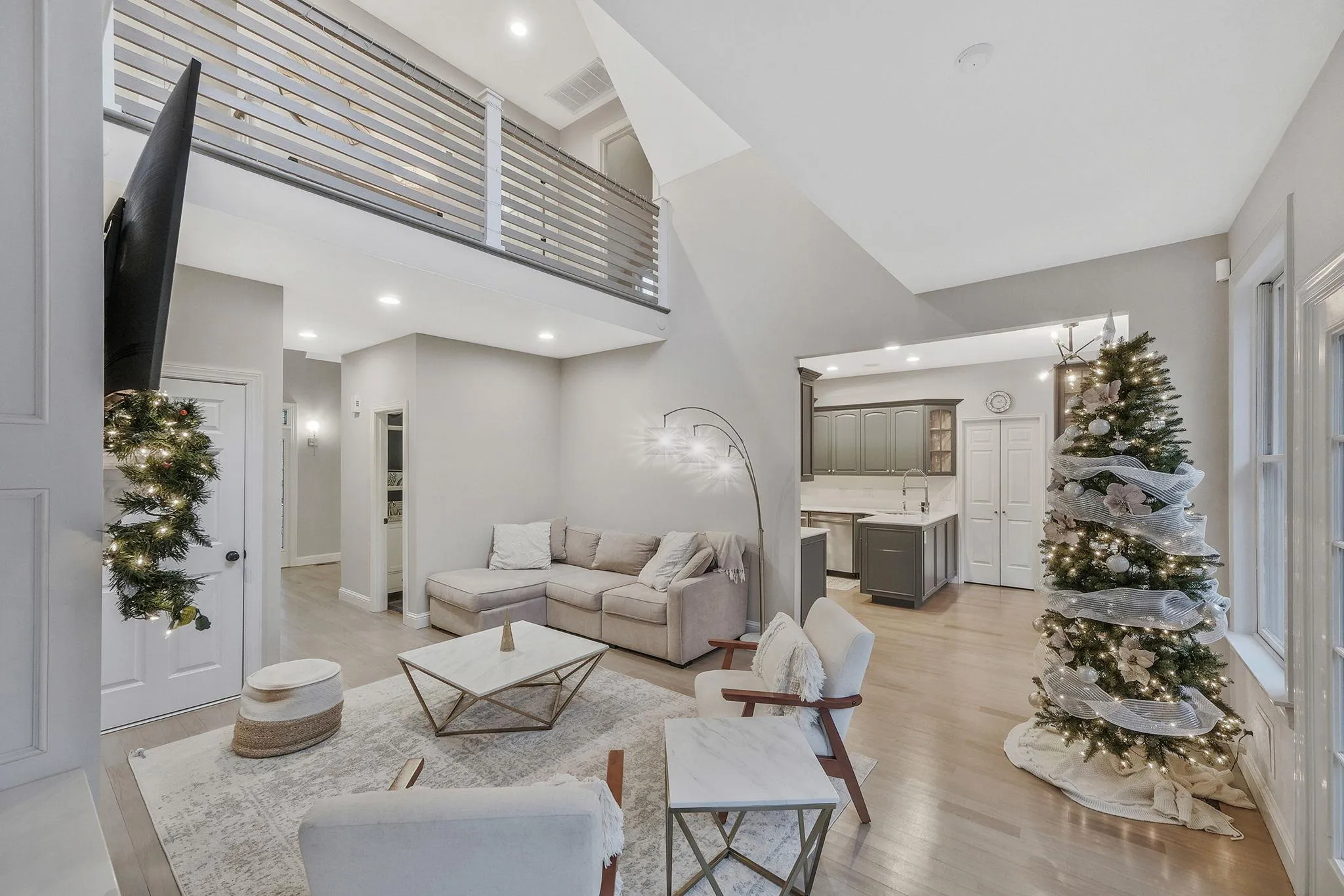 Living room with sink, a towering ceiling, and light hardwood / wood-style flooring Living room with sink, a towering ceiling, and light hardwood / wood-style flooring