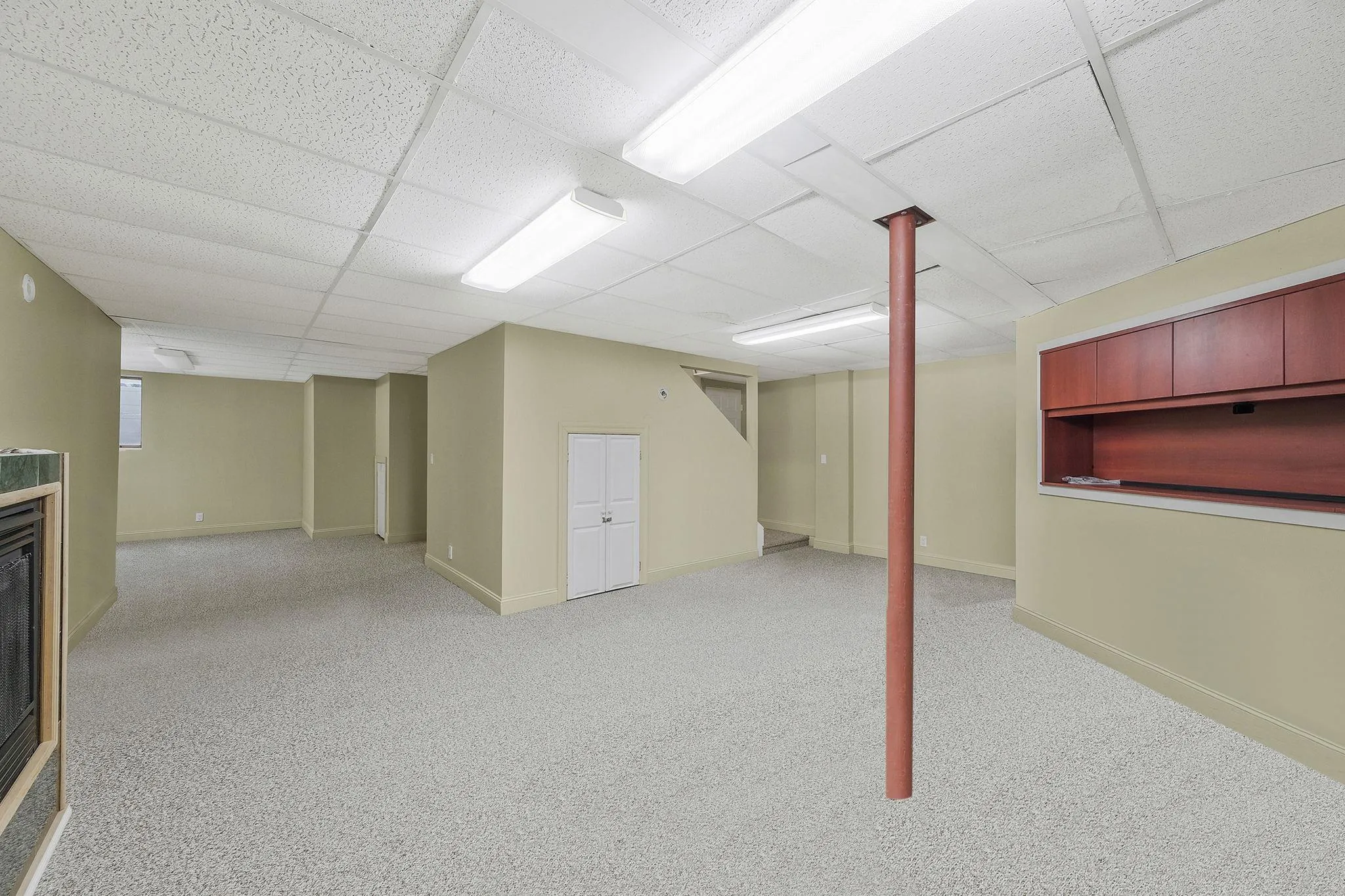 Basement with a paneled ceiling, light colored carpet, and built in features Basement with a paneled ceiling, light colored carpet, and built in features