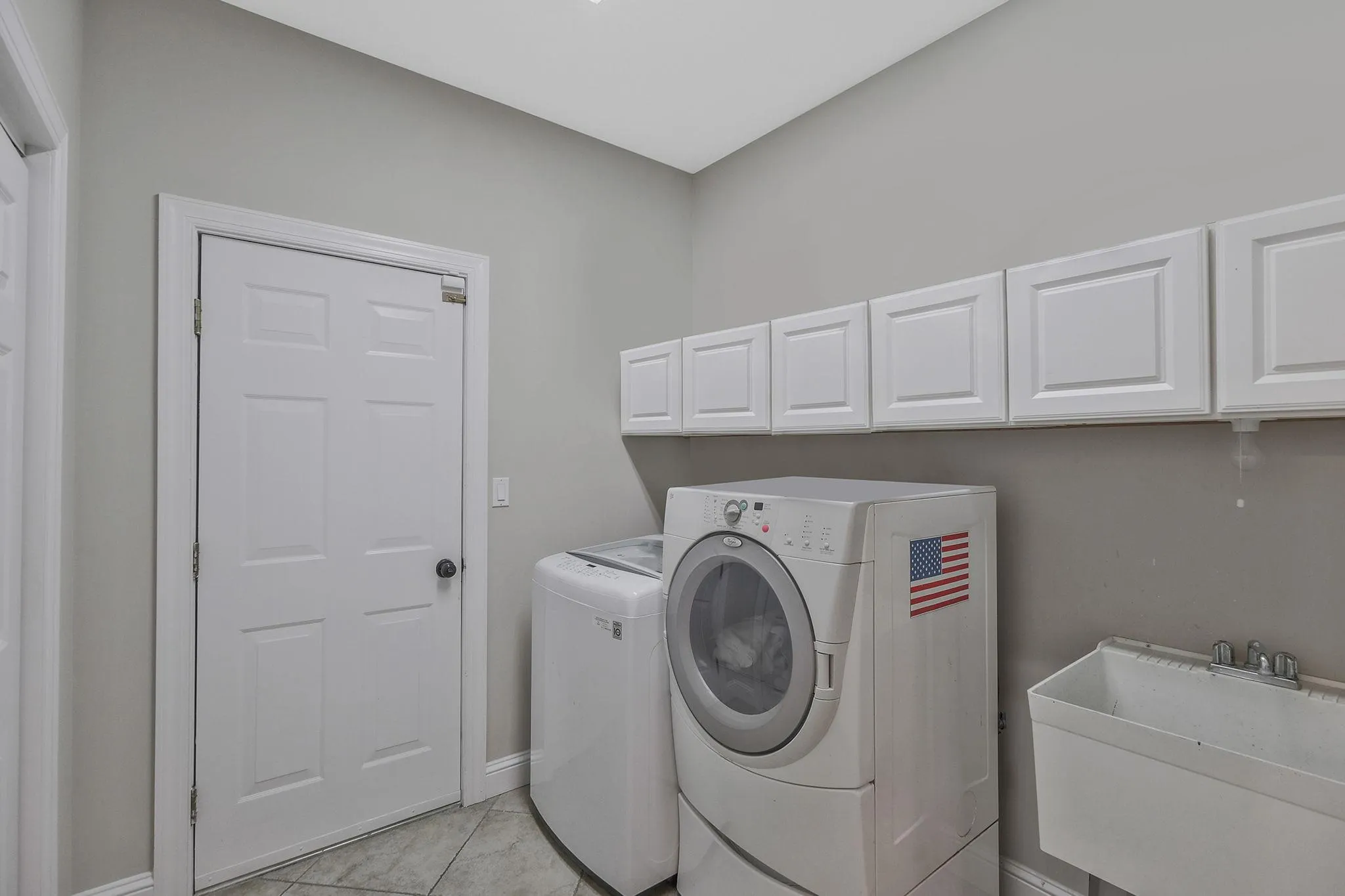 Laundry area with cabinets, light tile patterned floors, sink, and washing machine and dryer Laundry area with cabinets, light tile patterned floors, sink, and washing machine and dryer