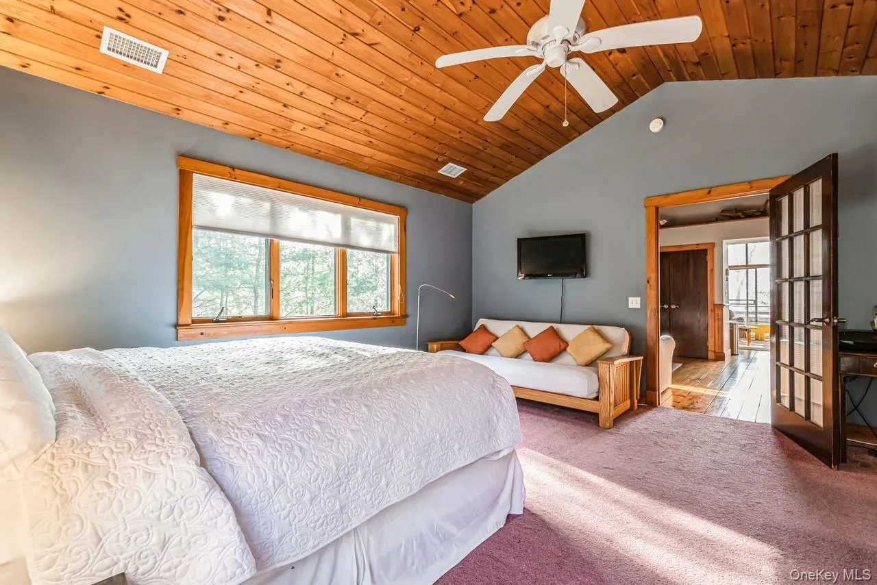 Bedroom with high ceiling, french door, ceiling fan, and wood ceiling
