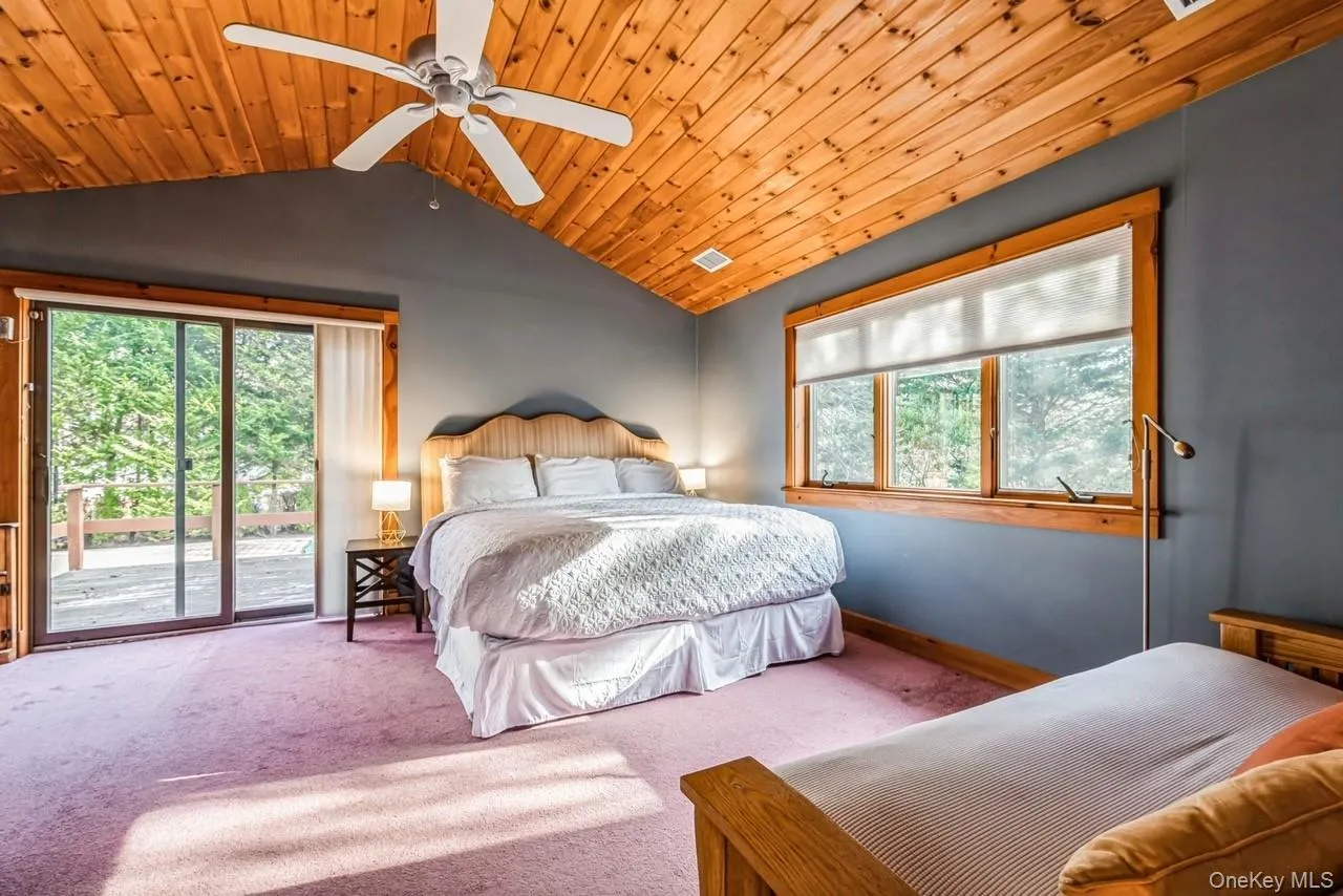 Primary bedroom featuring access to back deck, ceiling fan, wood ceiling, and high ceiling