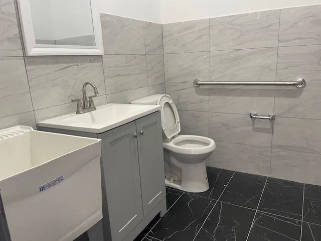 Bathroom with marble finish floors, tile walls, and vanity Bathroom with marble finish floors, tile walls, and vanity