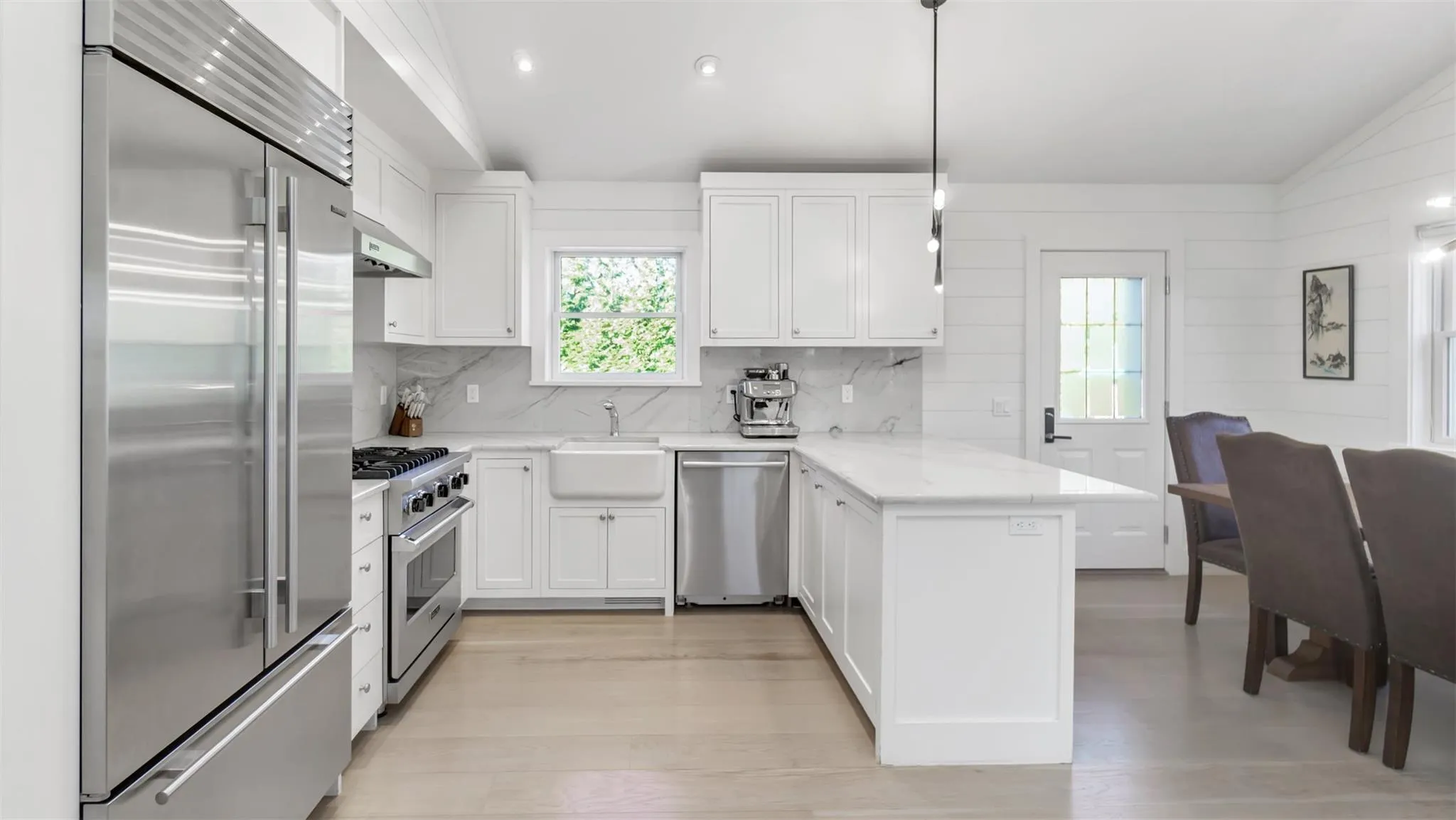 Kitchen featuring light stone countertops, hanging light fixtures, vaulted ceiling, white cabinets, and high end appliances Kitchen featuring light stone countertops, hanging light fixtures, vaulted ceiling, white cabinets, and high end appliances