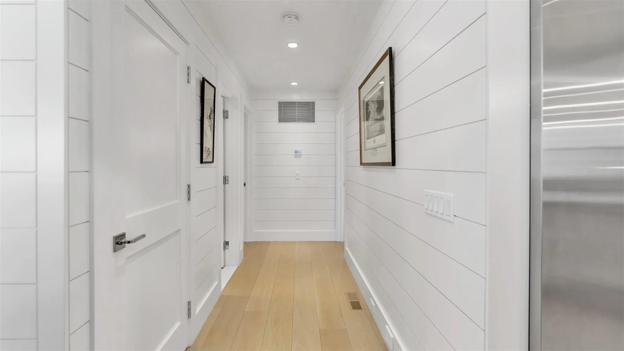 Hallway with light hardwood / wood-style floors, elevator, and wooden walls Hallway with light hardwood / wood-style floors, elevator, and wooden walls
