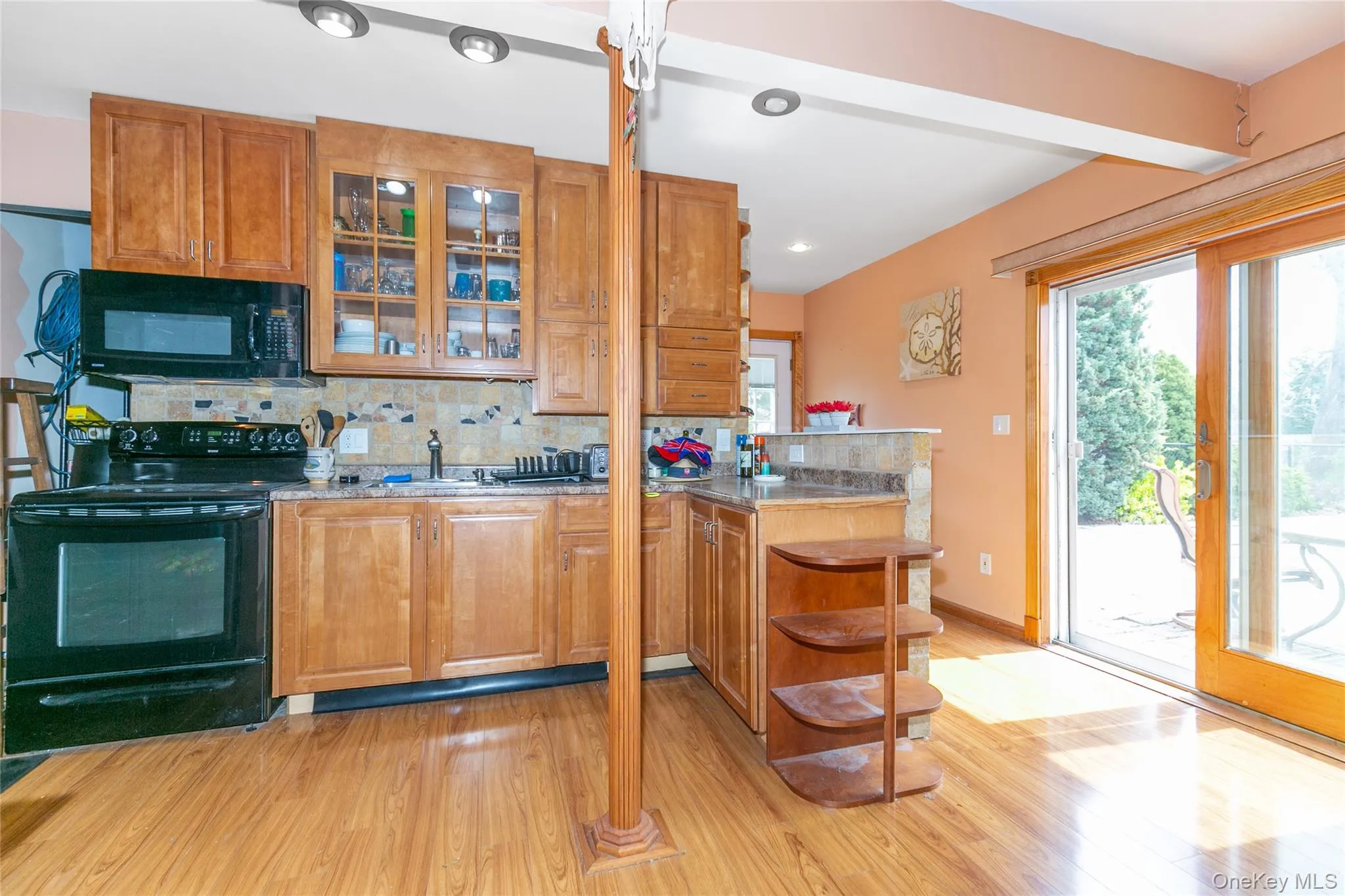 Kitchen with decorative backsplash, sink, light hardwood / wood-style floors, and black appliances Kitchen with decorative backsplash, sink, light hardwood / wood-style floors, and black appliances