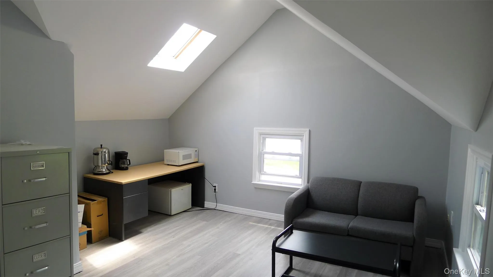 Home office with light hardwood / wood-style floors and lofted ceiling with skylight Home office with light hardwood / wood-style floors and lofted ceiling with skylight
