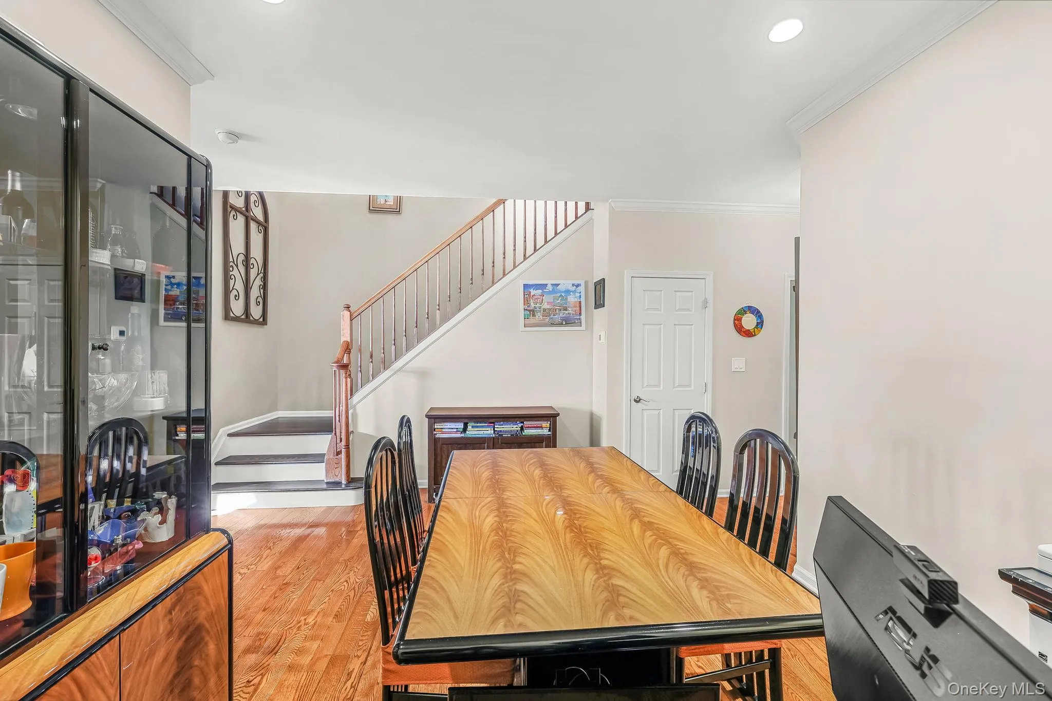 Hardwood flooring, painted interior walls, recessed lighting, white crown molding, and a staircase with wood handrails Hardwood flooring, painted interior walls, recessed lighting, white crown molding, and a staircase with wood handrails