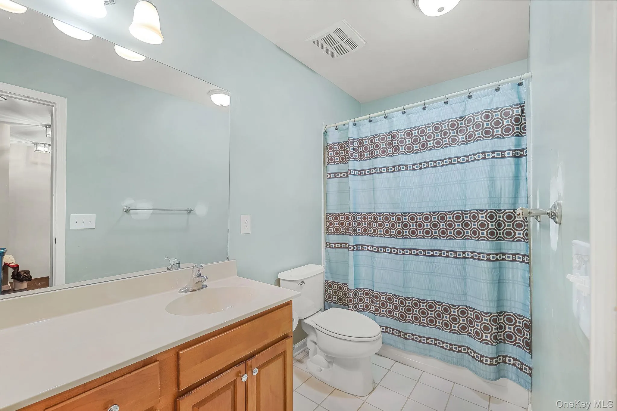 Bathroom featuring a neutral vanity with built-in storage, a white countertop, and a vanity mirror with overhead lighting Bathroom featuring a neutral vanity with built-in storage, a white countertop, and a vanity mirror with overhead lighting