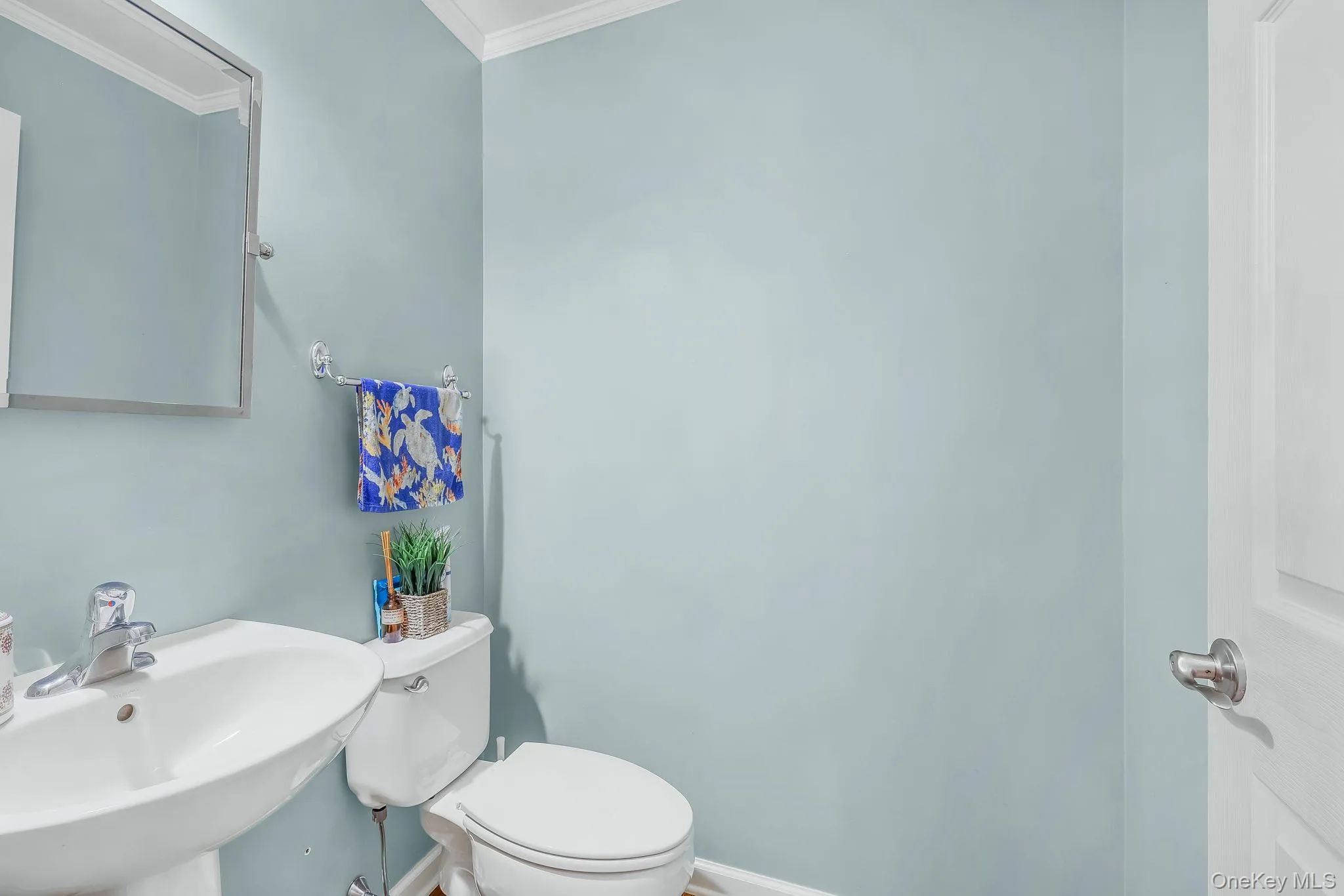 Pedestal sink with chrome-finish faucet, white toilet, and wall-mounted mirror Pedestal sink with chrome-finish faucet, white toilet, and wall-mounted mirror