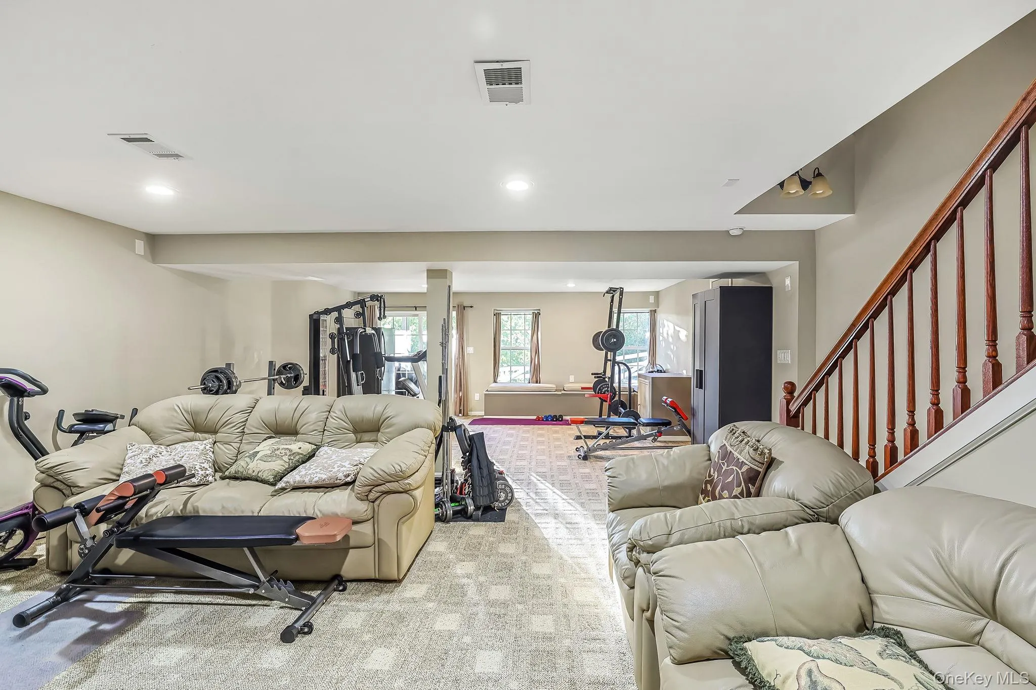 Recessed lighting, wood-finish stair railing, and a neutral wall color and sliders to outdoor patio Recessed lighting, wood-finish stair railing, and a neutral wall color and sliders to outdoor patio