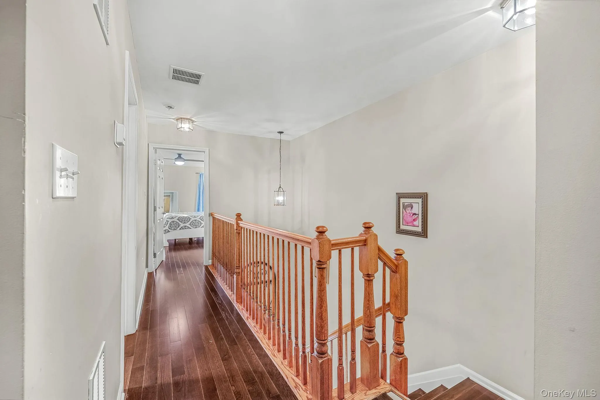 Hardwood flooring, wood spindle railing, recessed lighting, and a pendant light fixture Hardwood flooring, wood spindle railing, recessed lighting, and a pendant light fixture