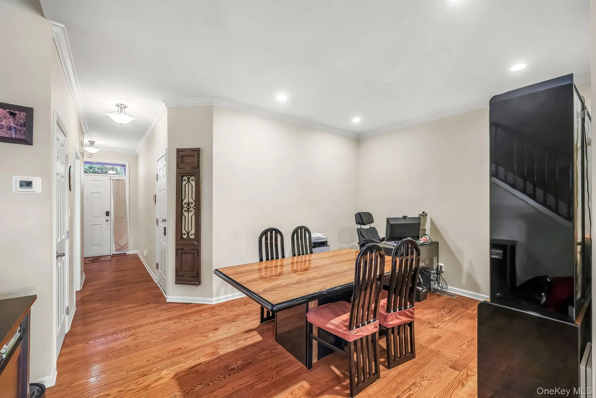 Hardwood flooring, recessed ceiling lighting, crown molding, and a hallway leading to an entry door Hardwood flooring, recessed ceiling lighting, crown molding, and a hallway leading to an entry door
