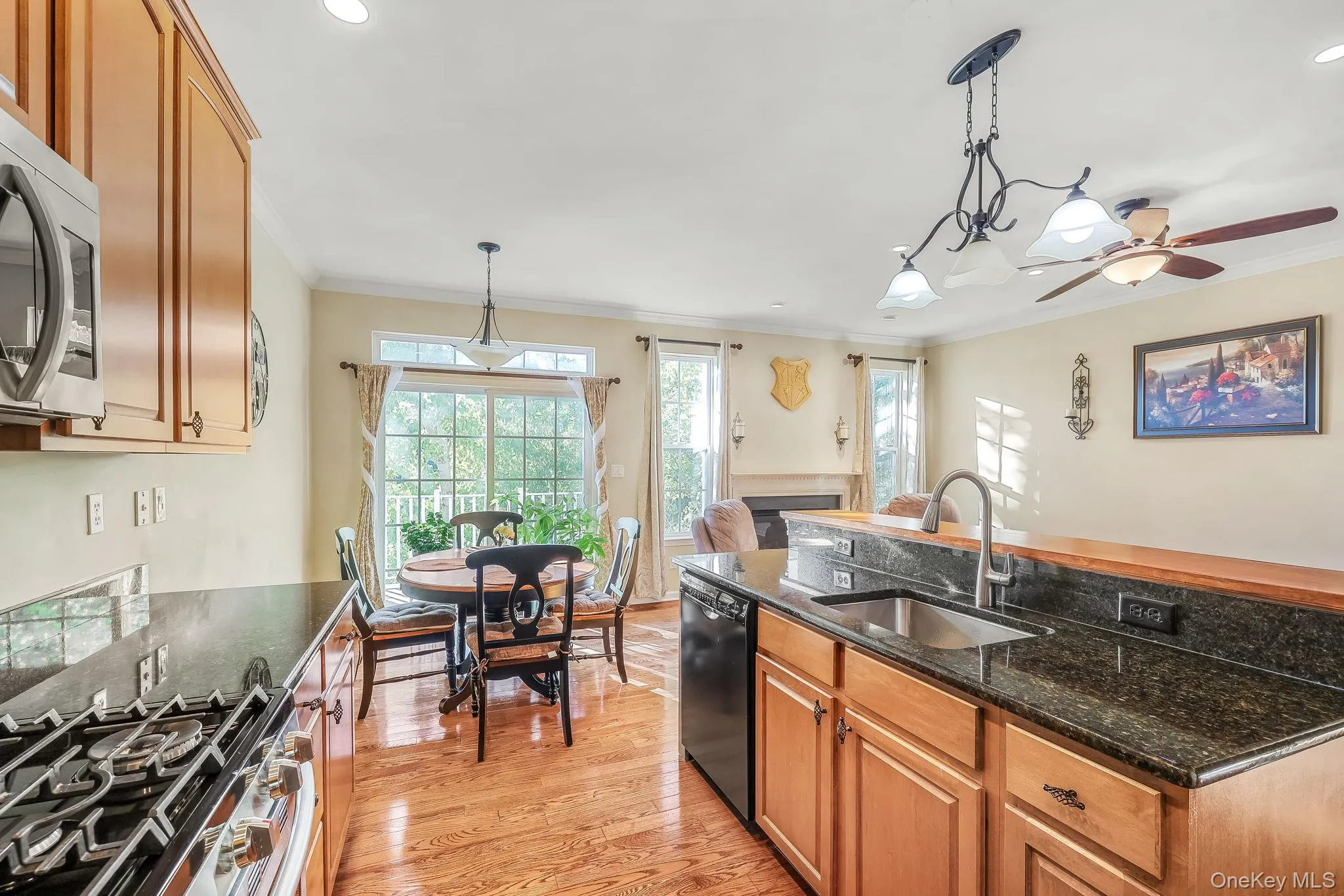Hardwood flooring, wood cabinetry, dark stone countertops, stainless steel appliances, and a built-in fireplace Hardwood flooring, wood cabinetry, dark stone countertops, stainless steel appliances, and a built-in fireplace