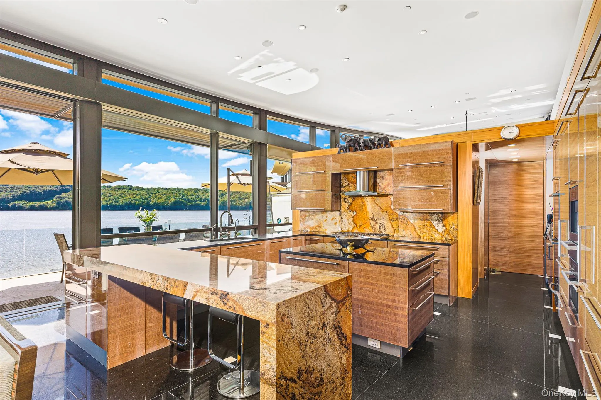 Kitchen with sink, wall chimney exhaust hood, a kitchen island, backsplash, and a water view Kitchen with sink, wall chimney exhaust hood, a kitchen island, backsplash, and a water view