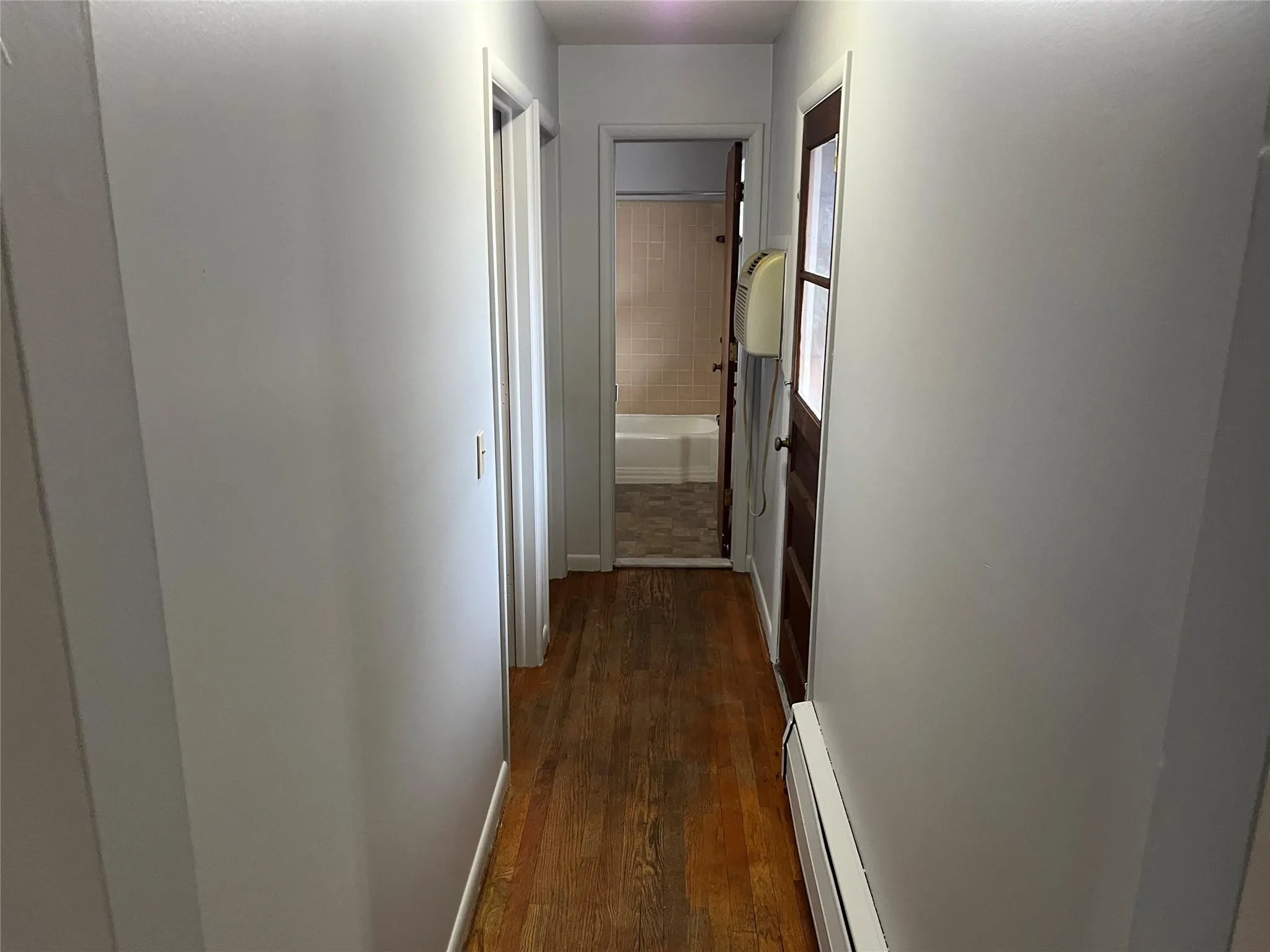 Corridor featuring dark hardwood / wood-style floors and baseboard heating Corridor featuring dark hardwood / wood-style floors and baseboard heating