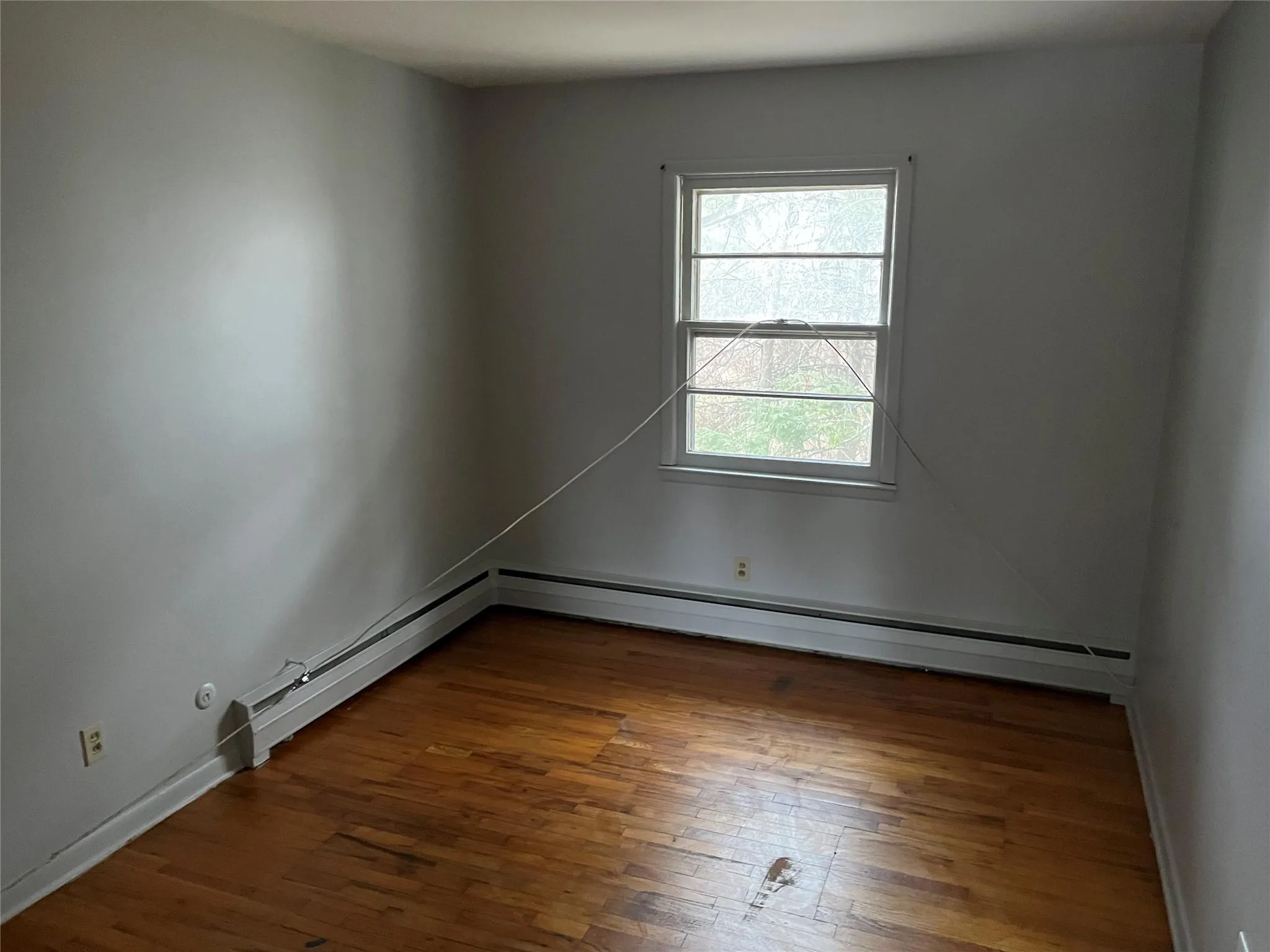Empty room featuring baseboard heating and dark wood-type flooring Empty room featuring baseboard heating and dark wood-type flooring