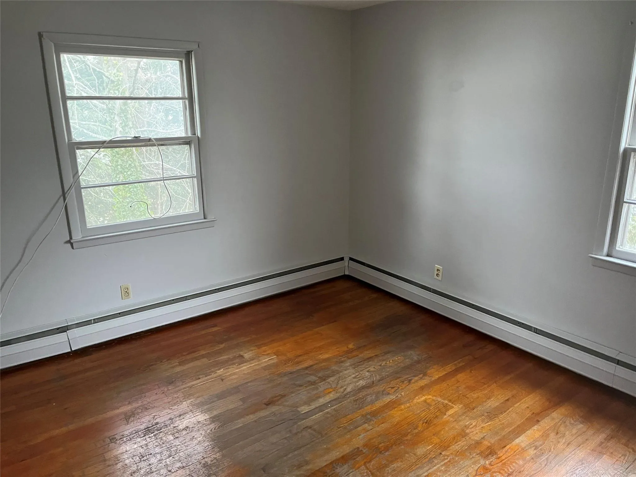 Unfurnished room with dark hardwood / wood-style floors and a baseboard heating unit Unfurnished room with dark hardwood / wood-style floors and a baseboard heating unit
