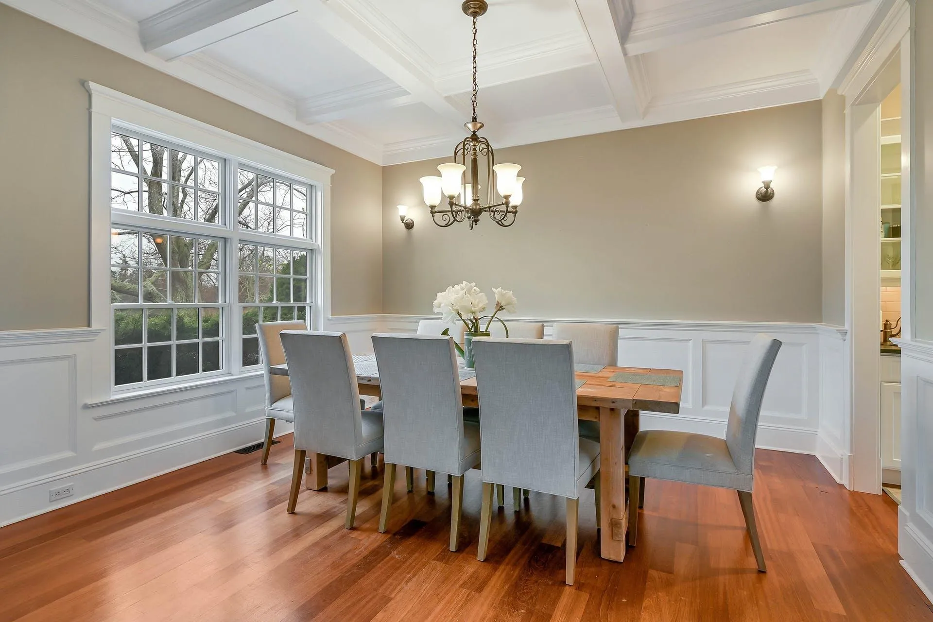 Dining room featuring coffered ceiling, crown molding, light hardwood / wood-style flooring, beamed ceiling, and a chandelier Dining room featuring coffered ceiling, crown molding, light hardwood / wood-style flooring, beamed ceiling, and a chandelier