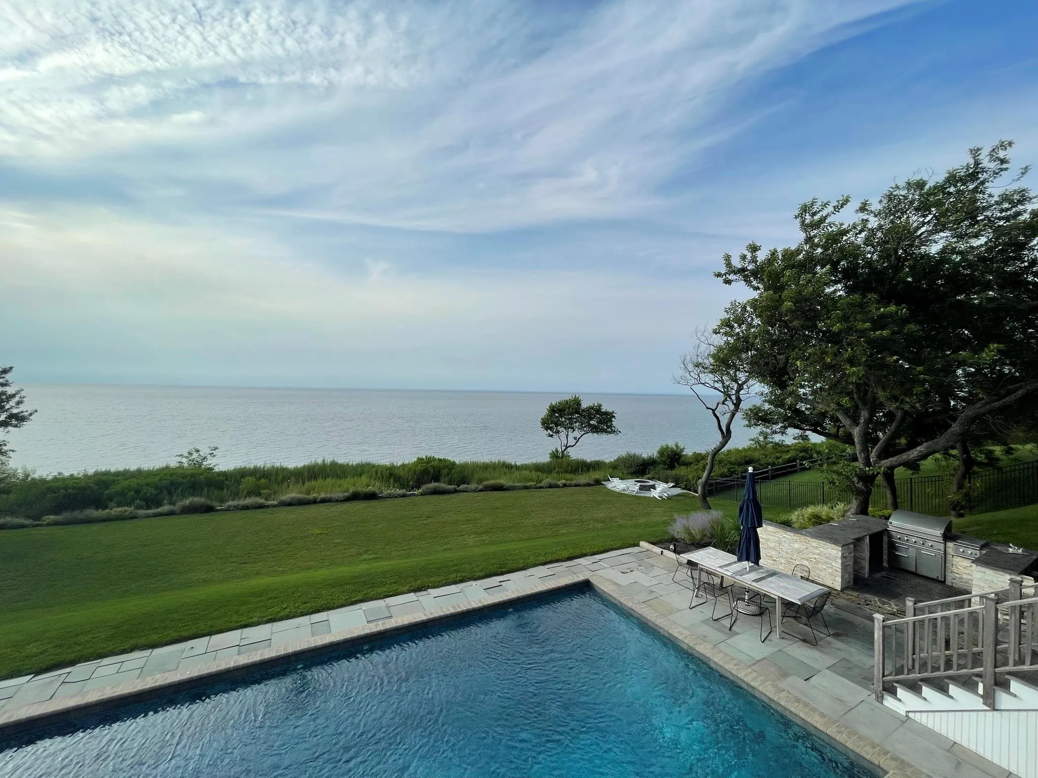 View of swimming pool with a lawn, a water view, a patio, and an outdoor kitchen View of swimming pool with a lawn, a water view, a patio, and an outdoor kitchen