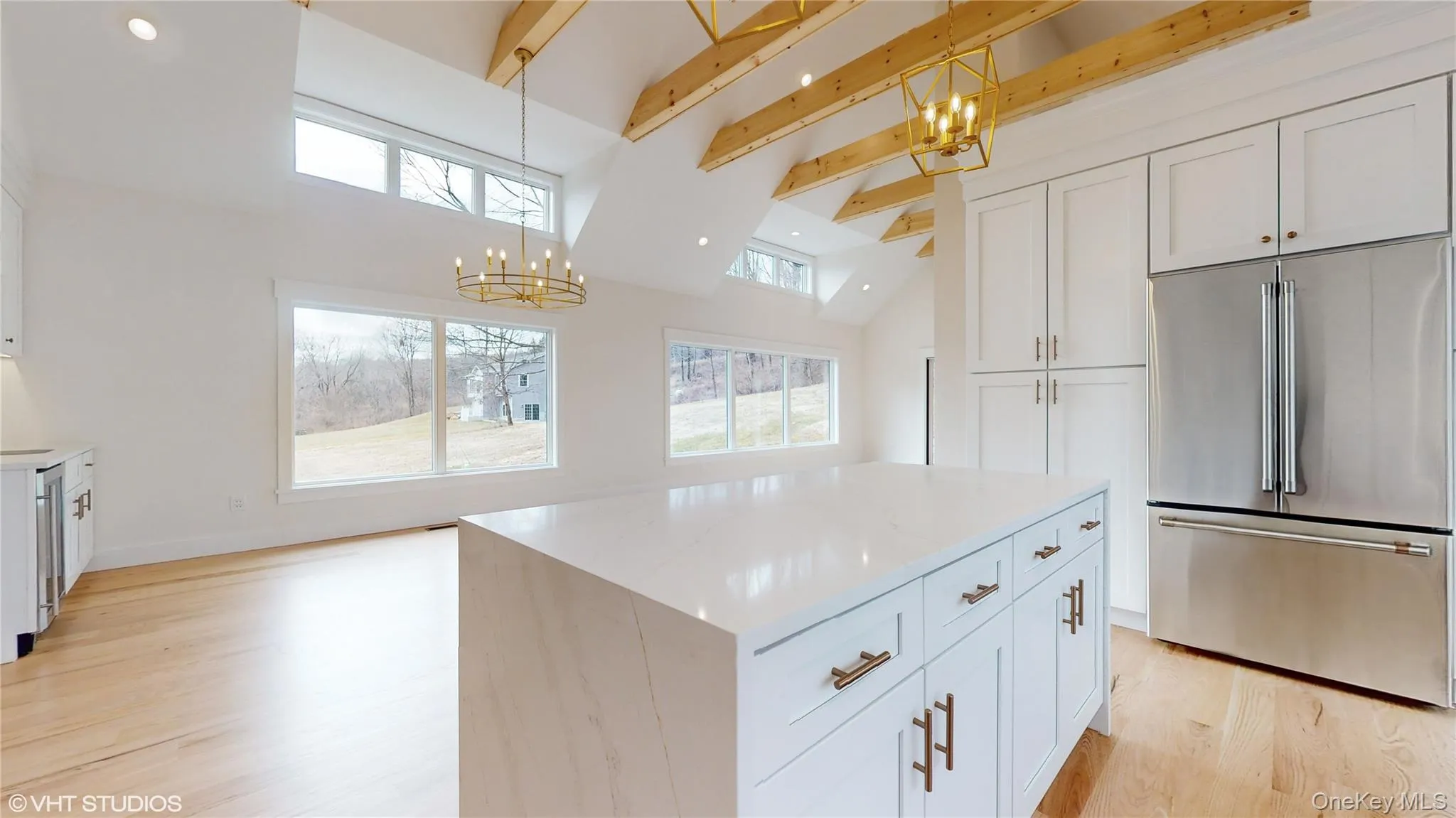 Kitchen with white cabinets, a center island, stainless steel appliances, and hanging light fixtures Kitchen with white cabinets, a center island, stainless steel appliances, and hanging light fixtures