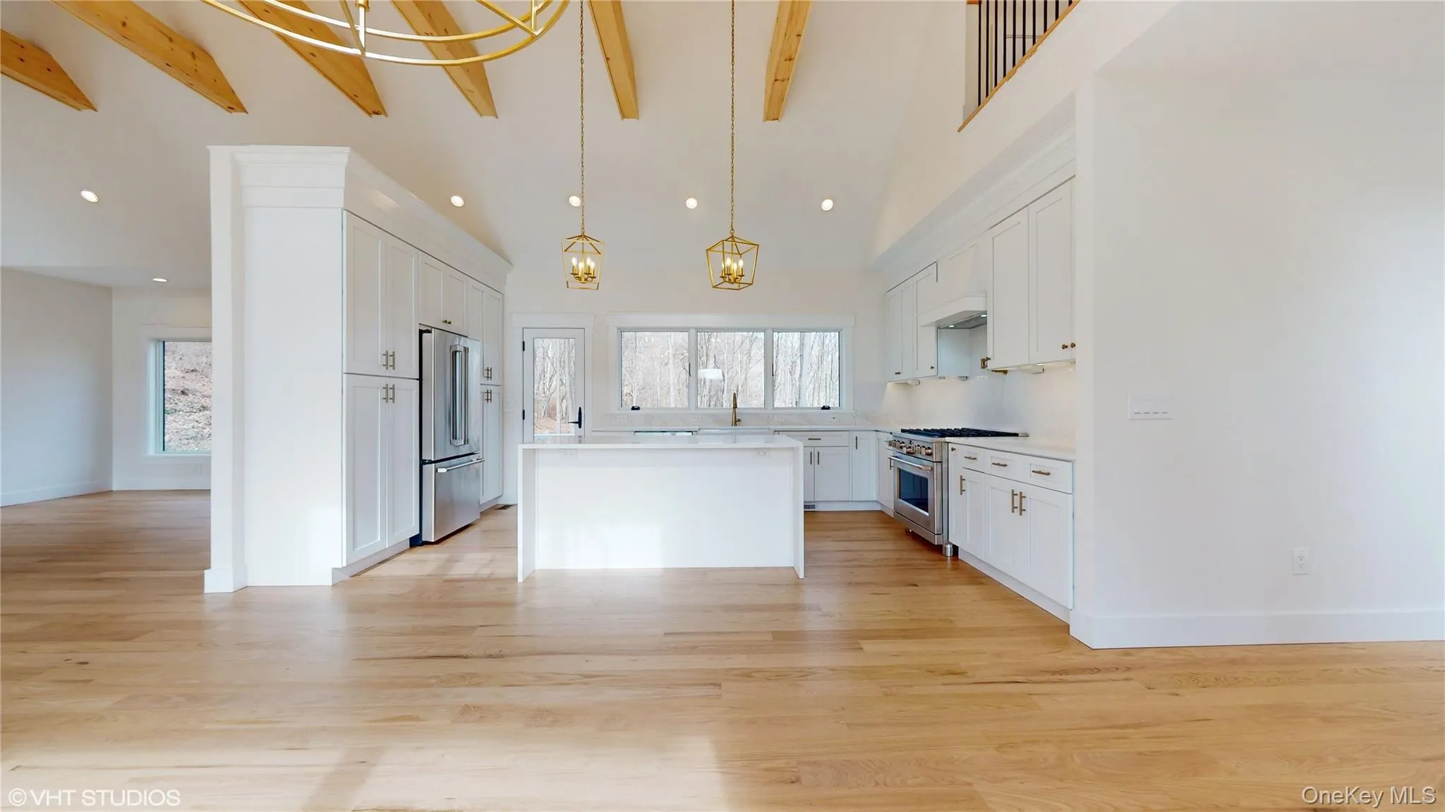Kitchen with beam ceiling, white cabinetry, premium appliances, pendant lighting, and a kitchen island Kitchen with beam ceiling, white cabinetry, premium appliances, pendant lighting, and a kitchen island