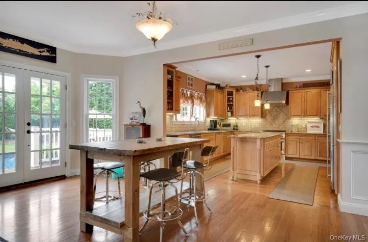 Kitchen featuring a center island, french doors, hanging light fixtures, light hardwood flooring, and tasteful backsplash Kitchen featuring a center island, french doors, hanging light fixtures, light hardwood flooring, and tasteful backsplash