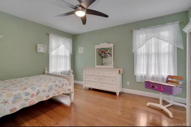 Bedroom featuring multiple windows, ceiling fan, and light wood-type flooring Bedroom featuring multiple windows, ceiling fan, and light wood-type flooring