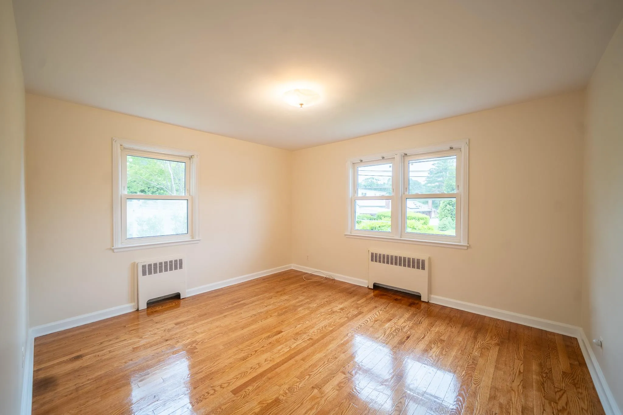 Spare room featuring radiator, healthy amount of natural light, and light wood-style floors Spare room featuring radiator, healthy amount of natural light, and light wood-style floors