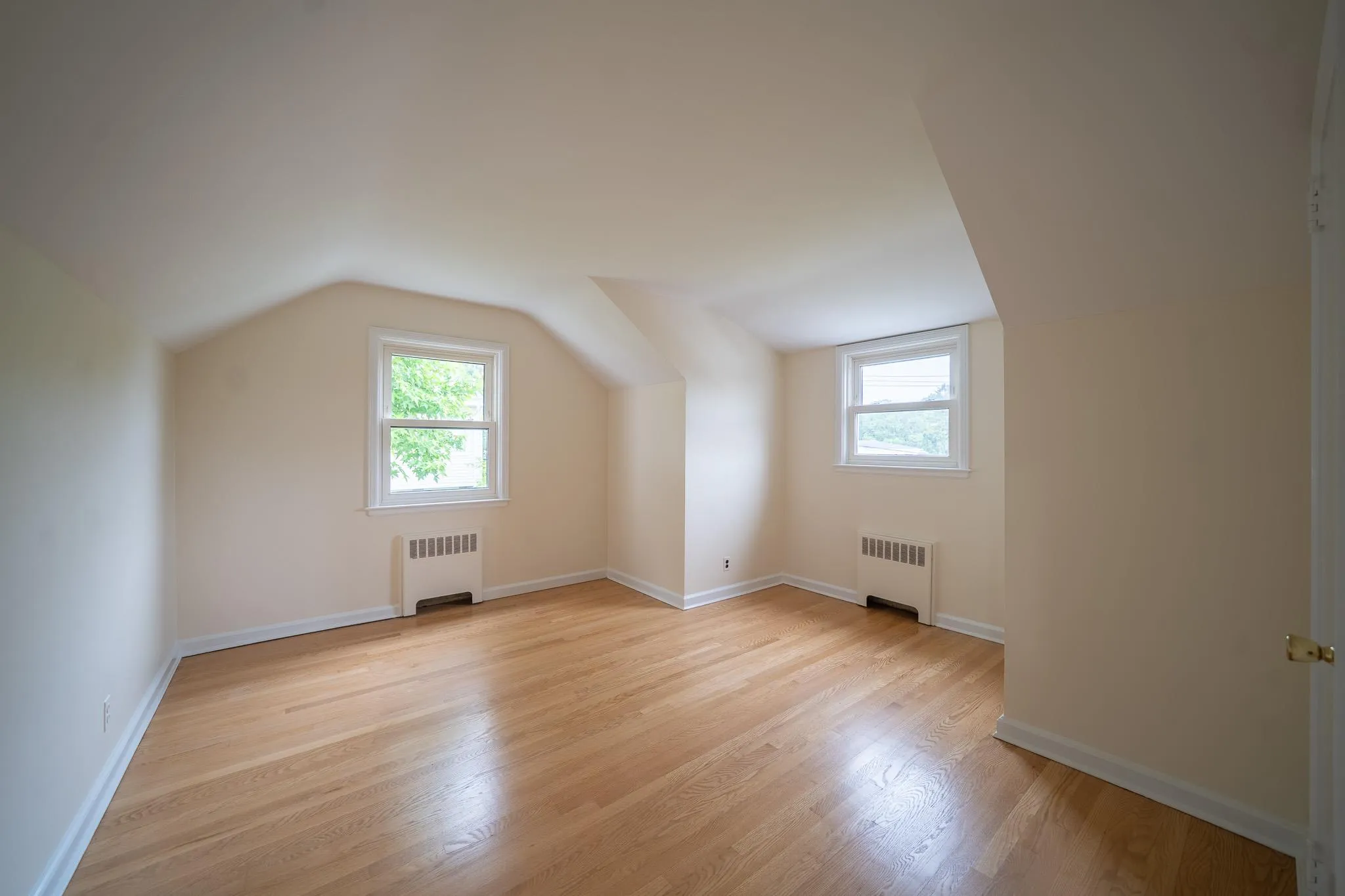 Bonus room with radiator heating unit, plenty of natural light, lofted ceiling, and light wood-style flooring Bonus room with radiator heating unit, plenty of natural light, lofted ceiling, and light wood-style flooring