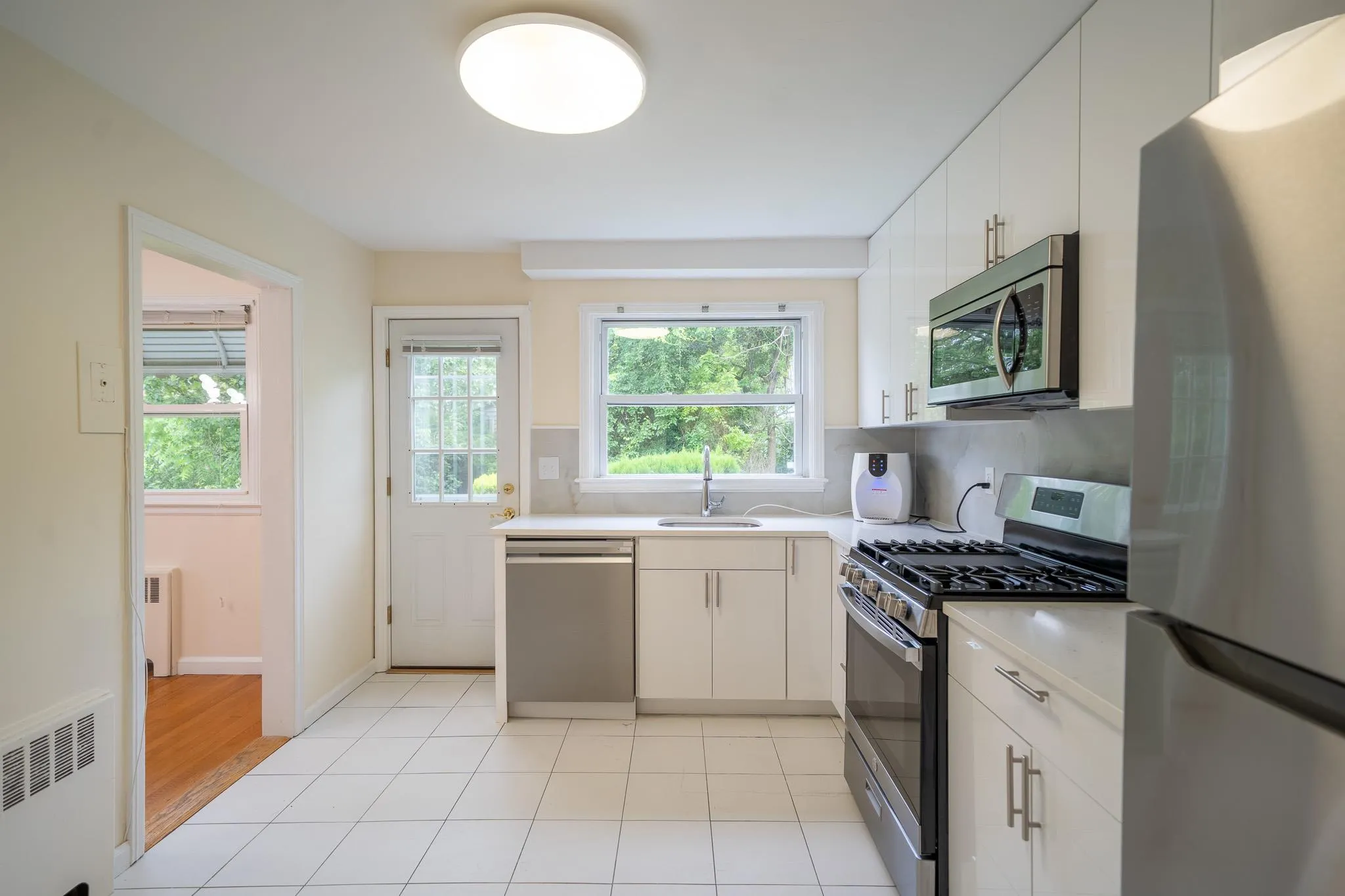 Kitchen featuring stainless steel appliances, radiator heating unit, and light countertops Kitchen featuring stainless steel appliances, radiator heating unit, and light countertops