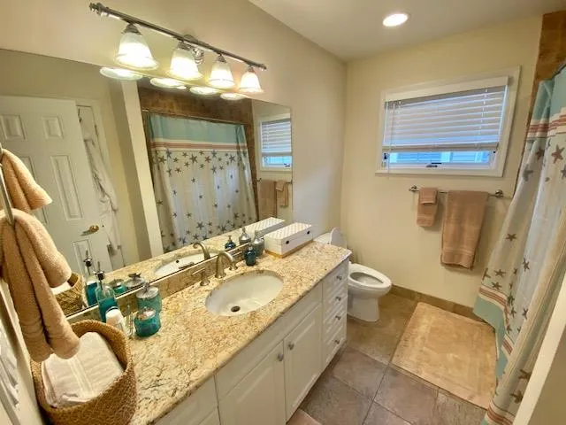 Bathroom with tile patterned floors, vanity, toilet, and curtained shower Bathroom with tile patterned floors, vanity, toilet, and curtained shower