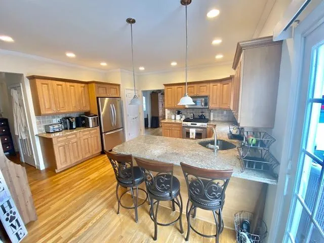 Kitchen featuring backsplash, kitchen peninsula, pendant lighting, and appliances with stainless steel finishes Kitchen featuring backsplash, kitchen peninsula, pendant lighting, and appliances with stainless steel finishes