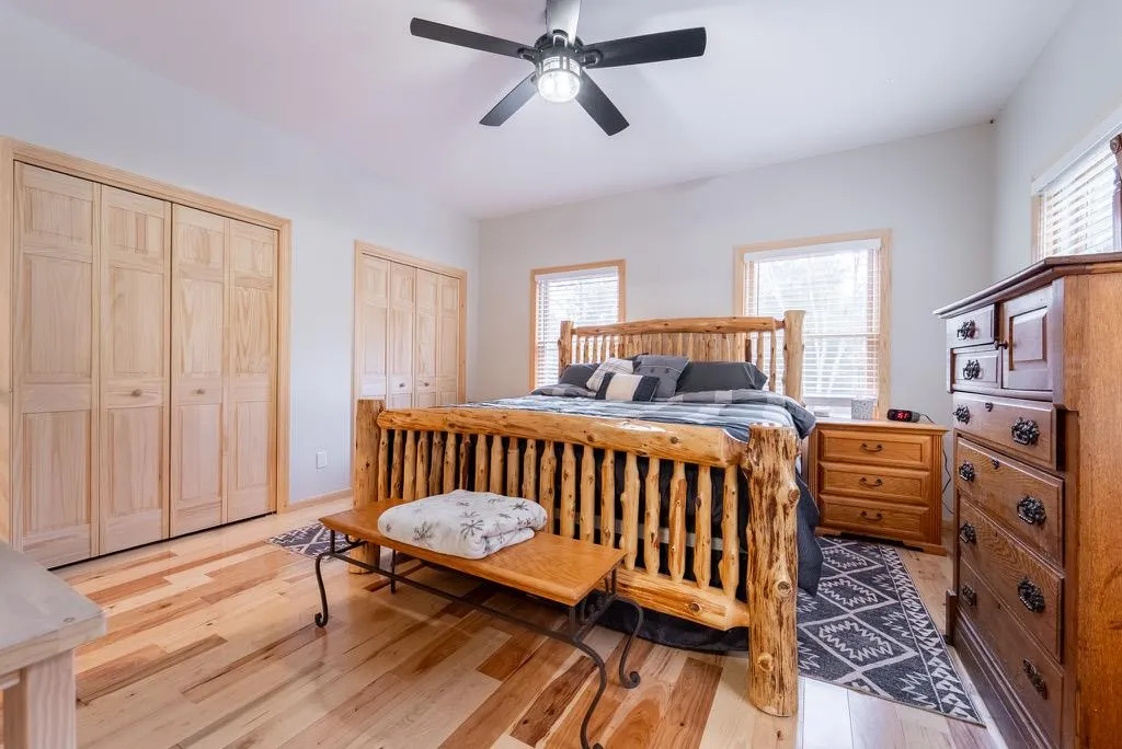 Bedroom featuring two closets, light hardwood / wood-style floors, and ceiling fan Bedroom featuring two closets, light hardwood / wood-style floors, and ceiling fan
