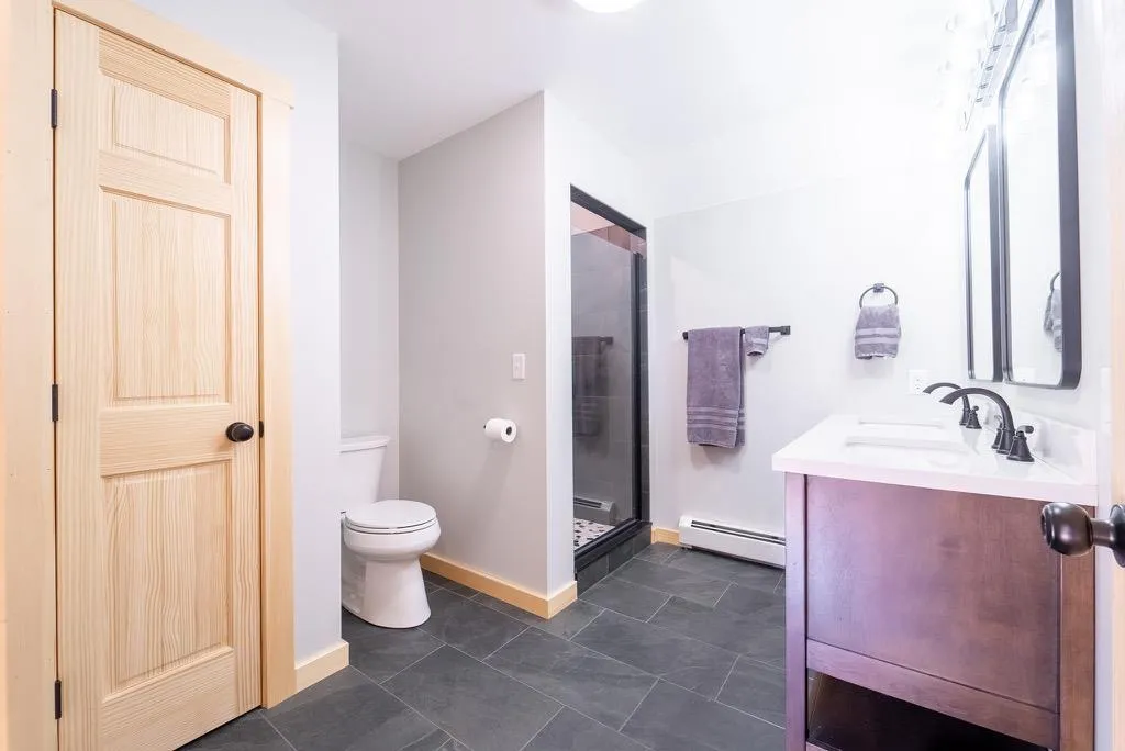 Bathroom featuring vanity, toilet, walk in shower, and a baseboard radiator Bathroom featuring vanity, toilet, walk in shower, and a baseboard radiator