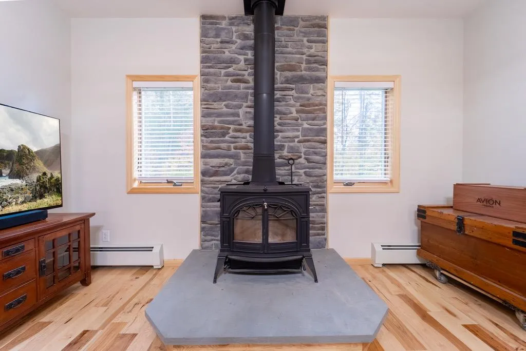 Living room featuring a wood stove, light hardwood / wood-style flooring, and a baseboard radiator Living room featuring a wood stove, light hardwood / wood-style flooring, and a baseboard radiator