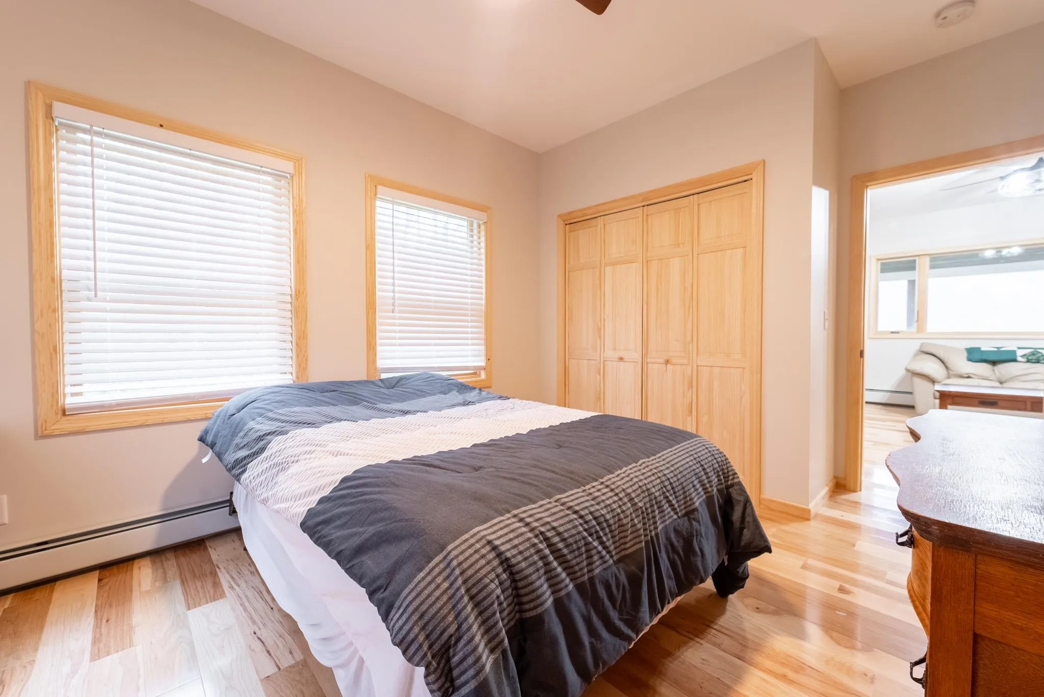 Bedroom with multiple windows, light wood-type flooring, baseboard heating, and a closet Bedroom with multiple windows, light wood-type flooring, baseboard heating, and a closet