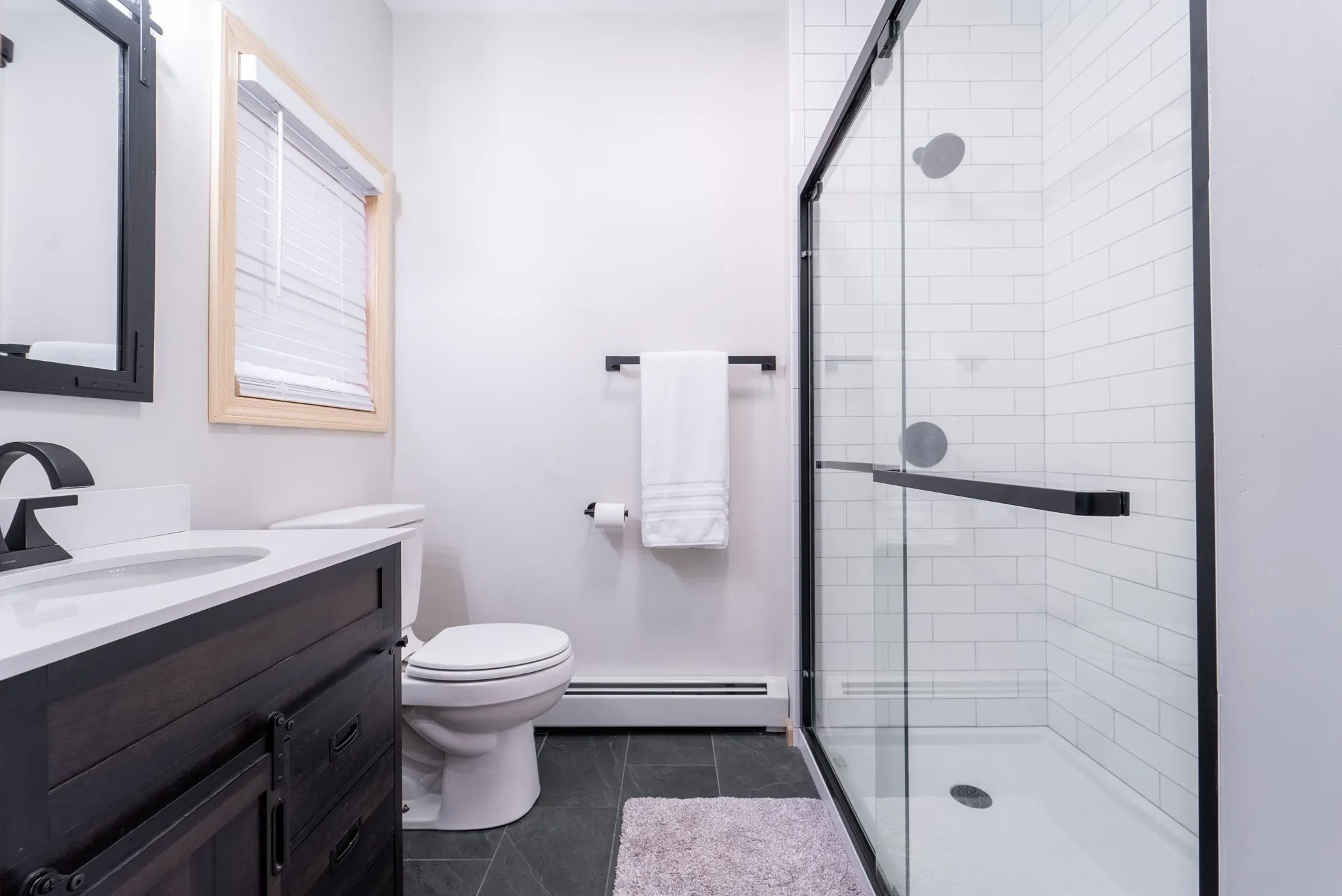 Bathroom featuring vanity, tile patterned floors, toilet, walk in shower, and a baseboard radiator Bathroom featuring vanity, tile patterned floors, toilet, walk in shower, and a baseboard radiator