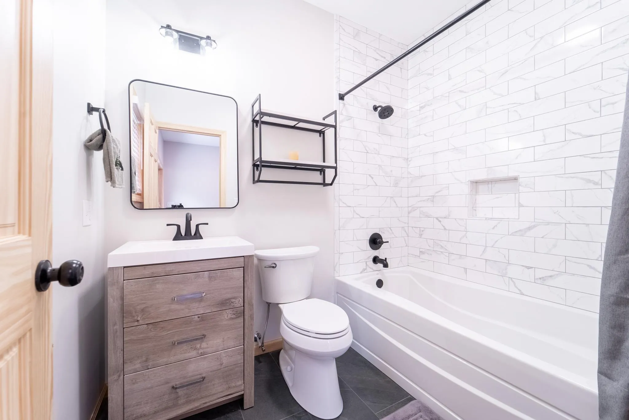 Full bathroom with tile patterned floors, vanity, toilet, and tiled shower / bath combo Full bathroom with tile patterned floors, vanity, toilet, and tiled shower / bath combo